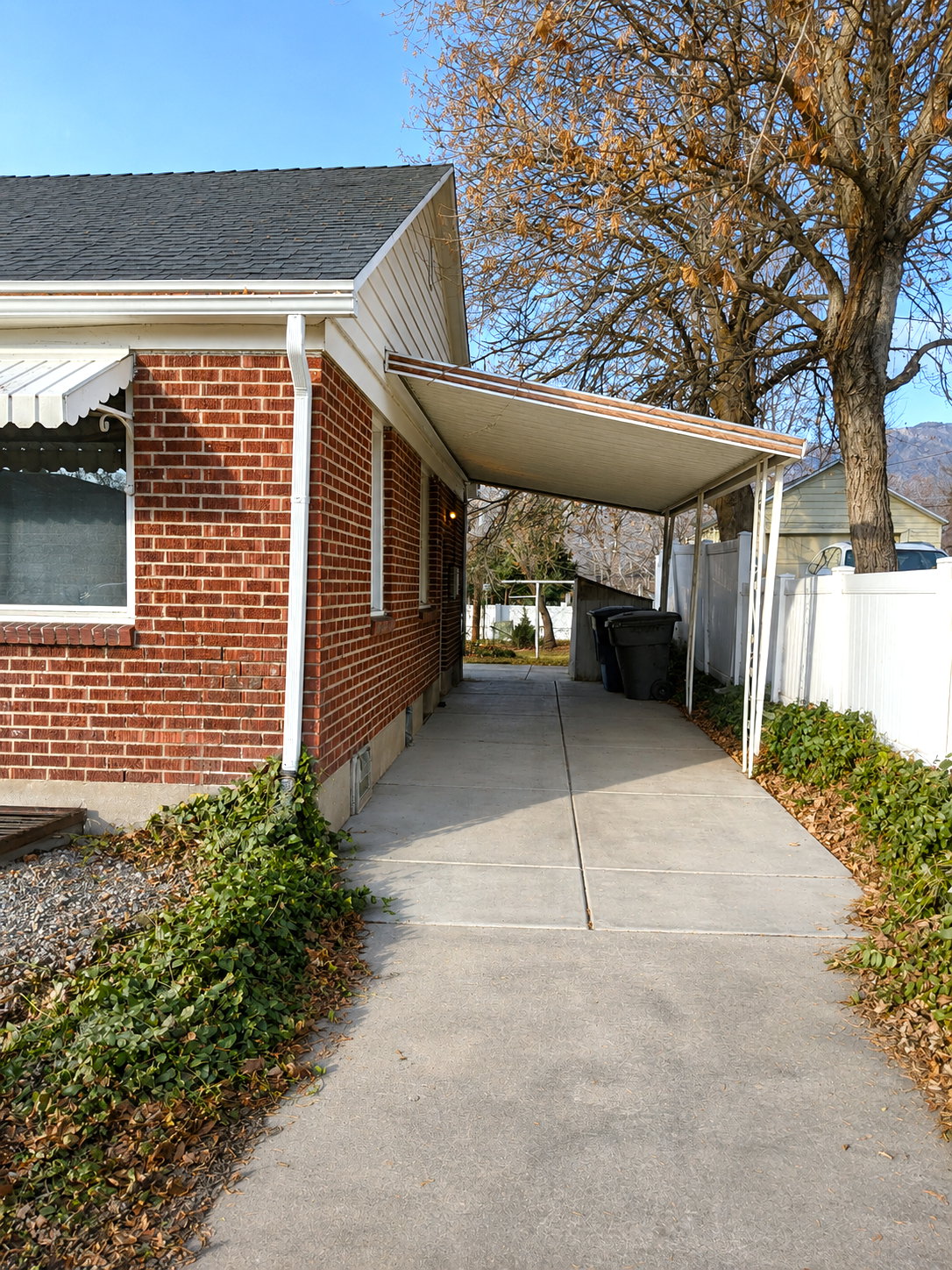 Side concrete driveway featuring a carport structure and brick exterior