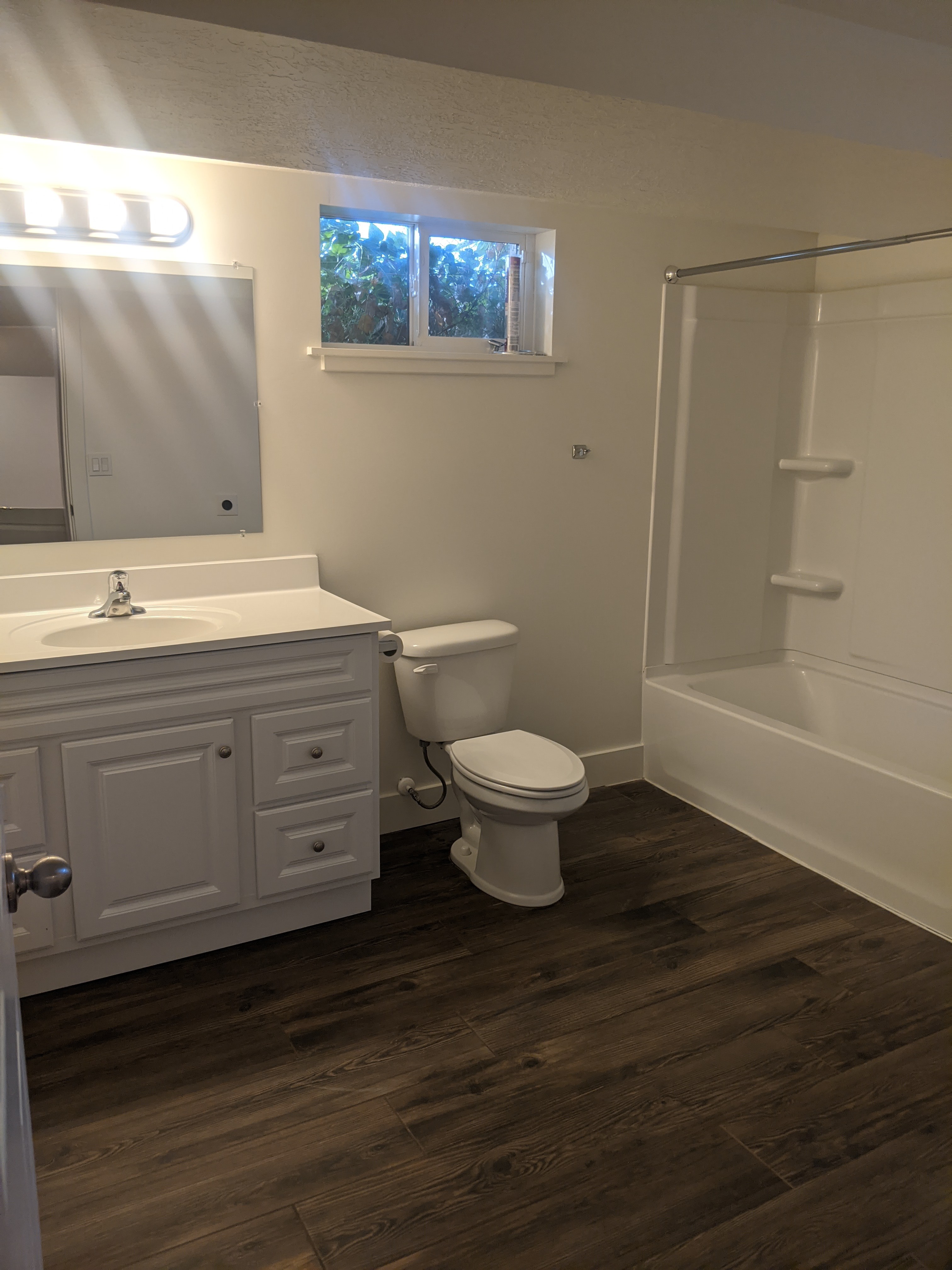 Bathroom featuring a white vanity with integrated sink, wood-finish flooring, and a white tub/shower combination
