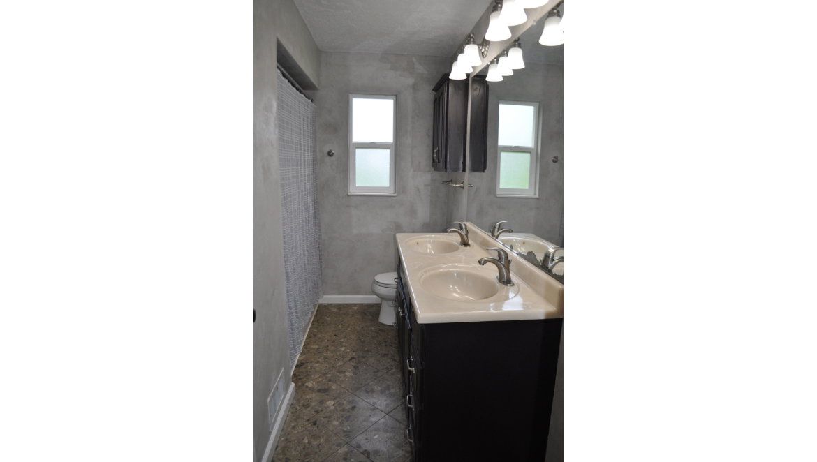 Bathroom featuring a dual vanity with integrated sinks, a full-width mirror, and a wall-mounted light fixture with six sconces