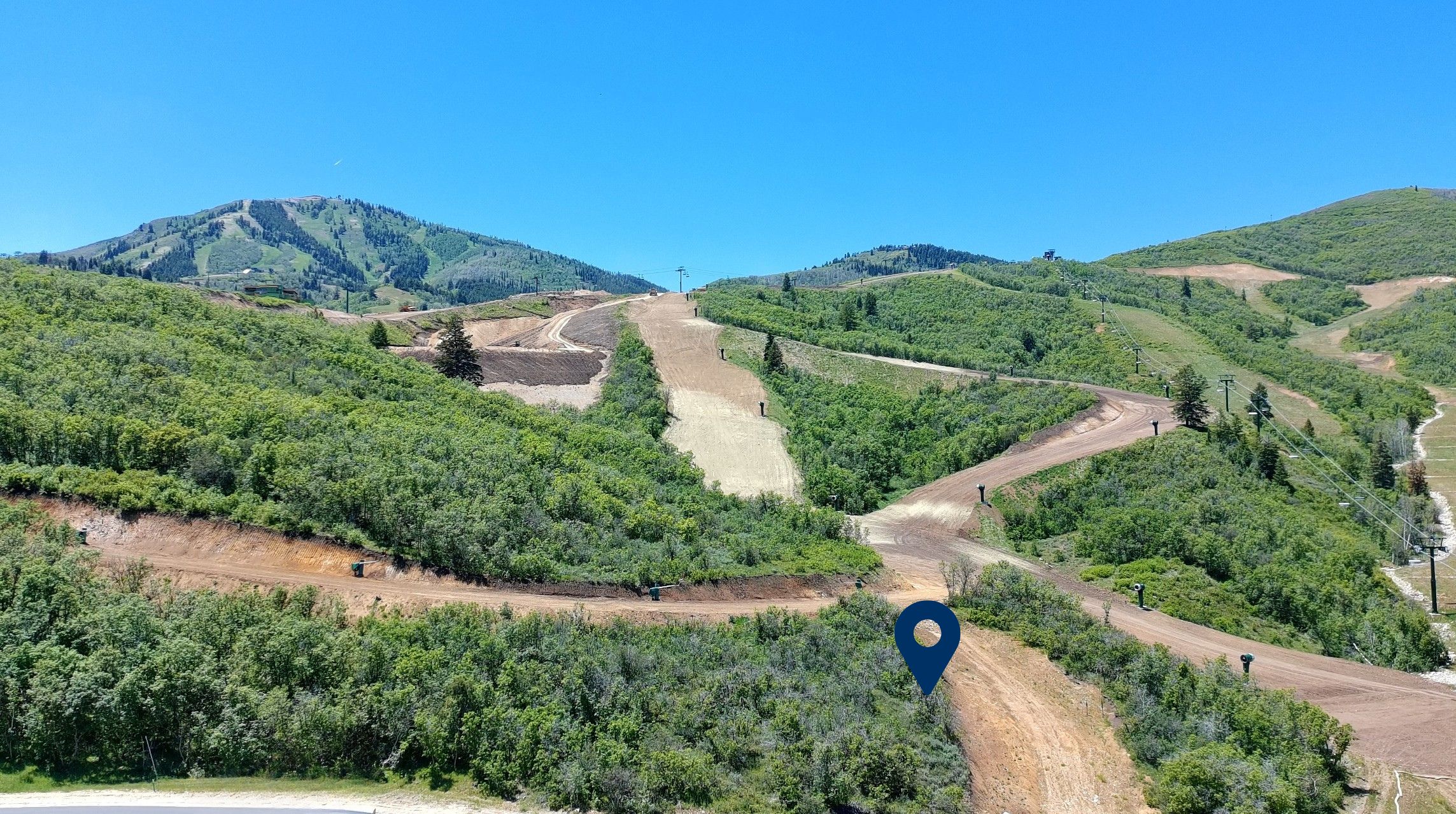 Expansive mountainous terrain featuring lush green foliage and visible ski runs