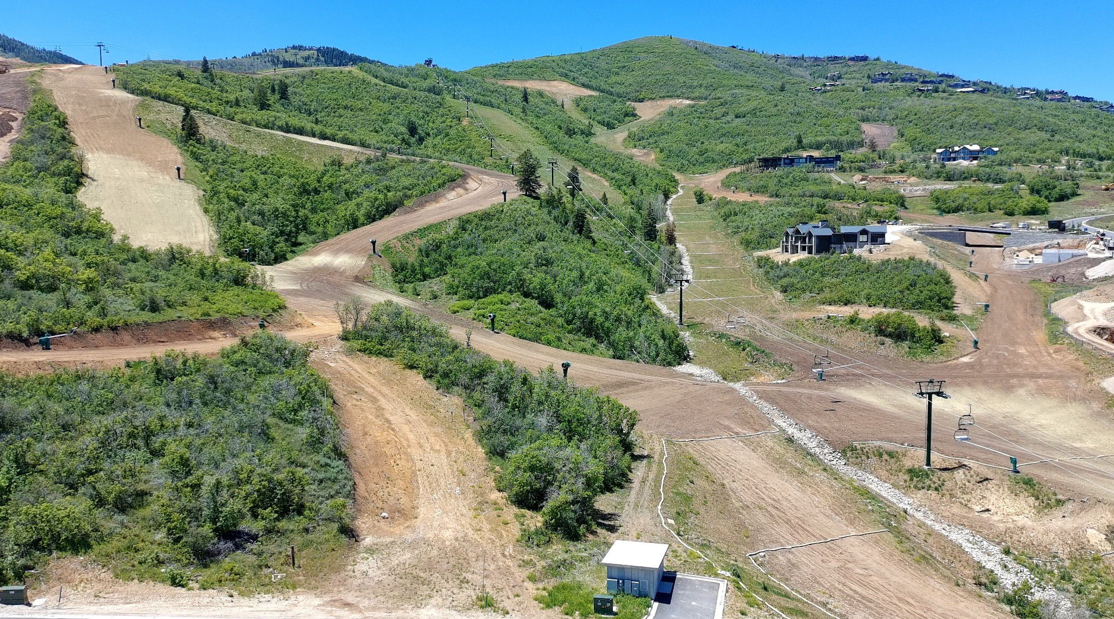 Expansive mountain terrain featuring verdant slopes, natural woodlands, and cleared areas