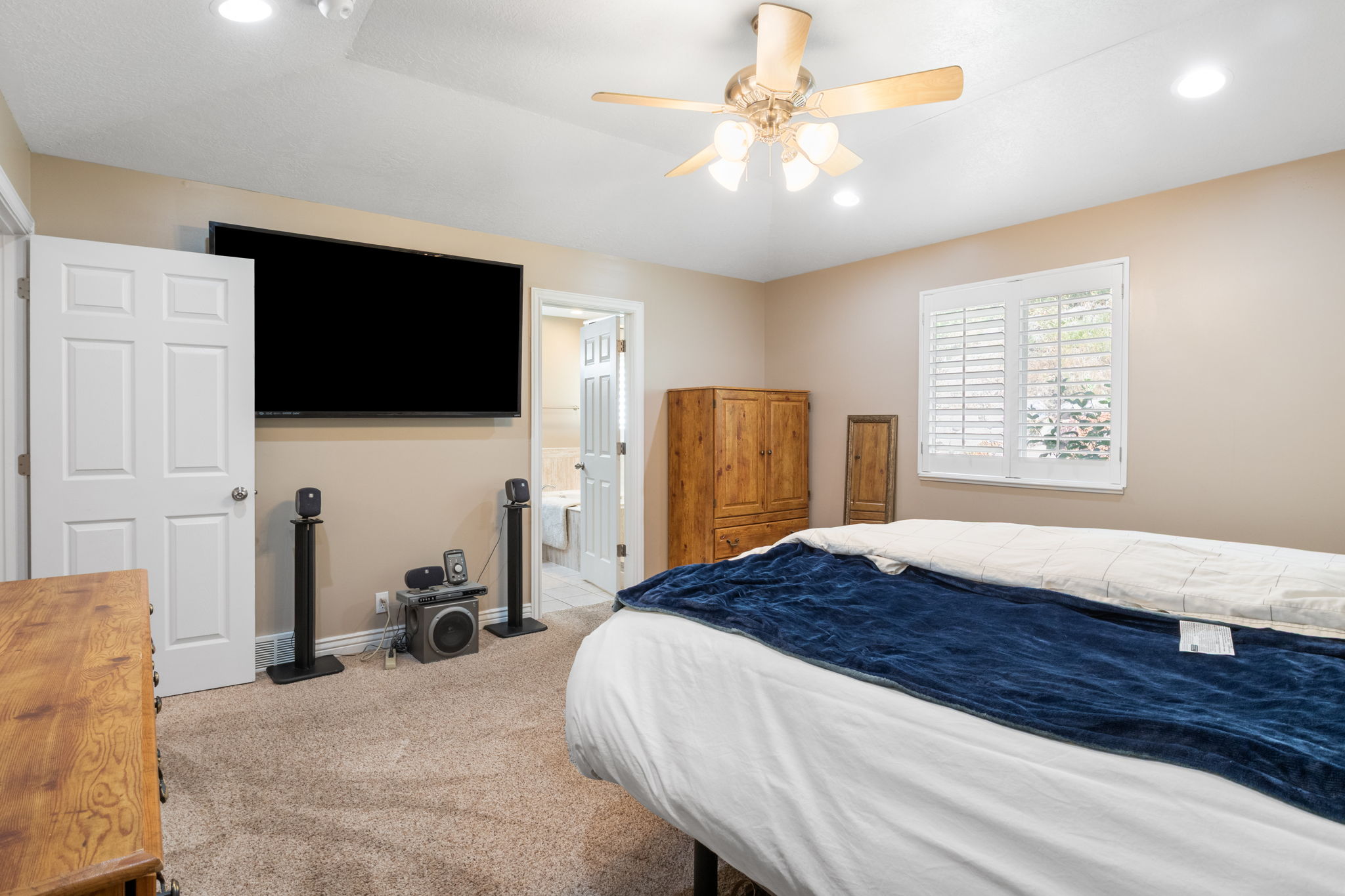 Carpeted room featuring a ceiling fan with integrated lighting, recessed lighting, and a window with white plantation shutters