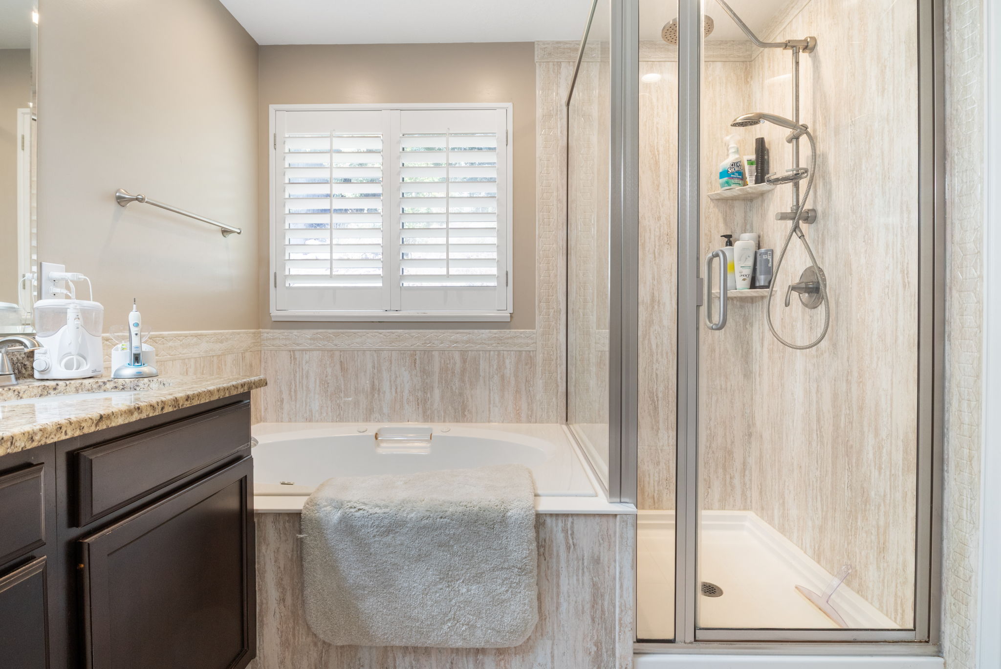 Walk-in shower with clear glass enclosure and light-toned shower surround