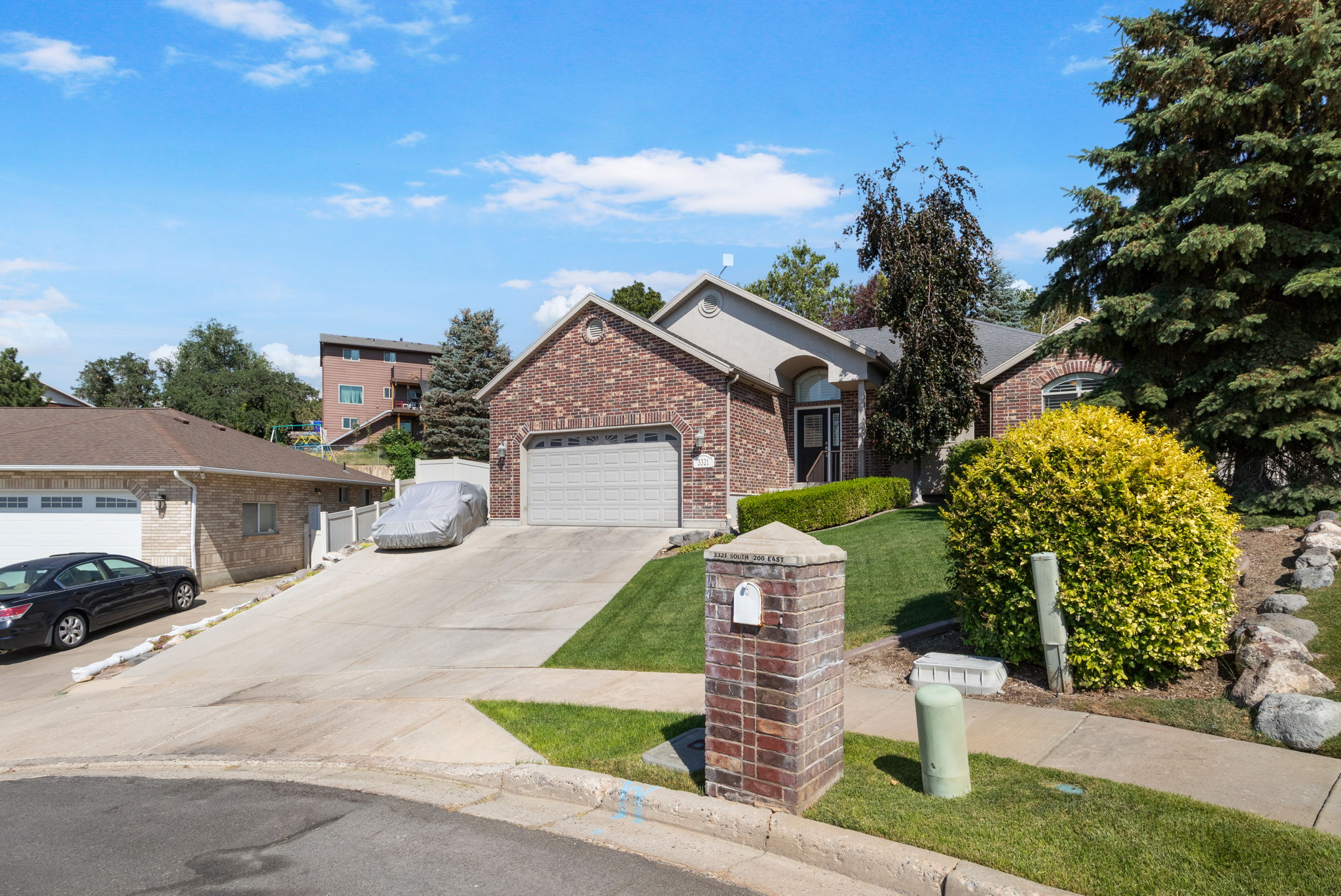 Brick facade residence featuring an attached two-car garage, arched entryways, and mature landscaping