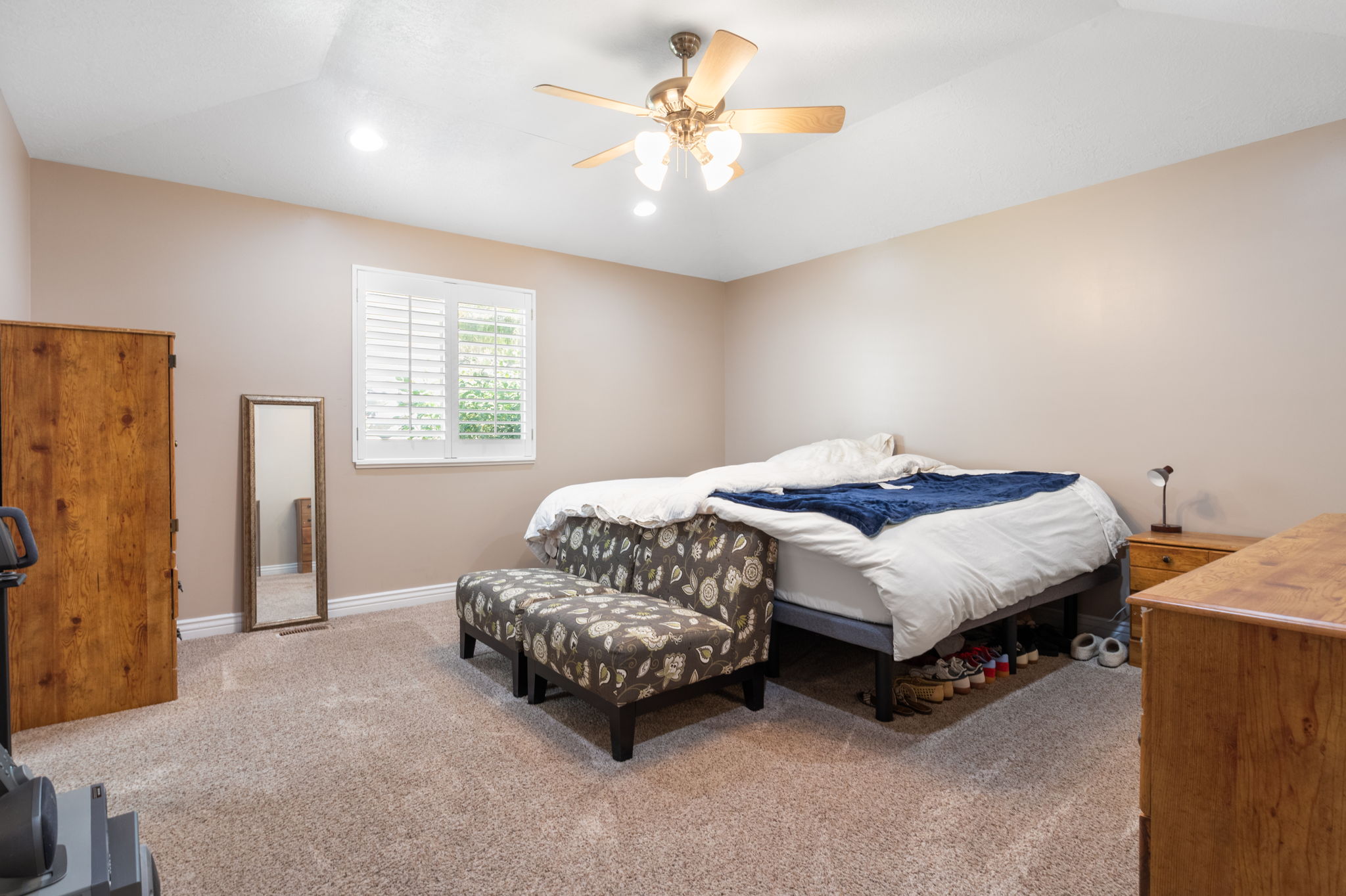 Carpeted room featuring a ceiling fan with integrated lighting, recessed lighting, and a window with white plantation shutters