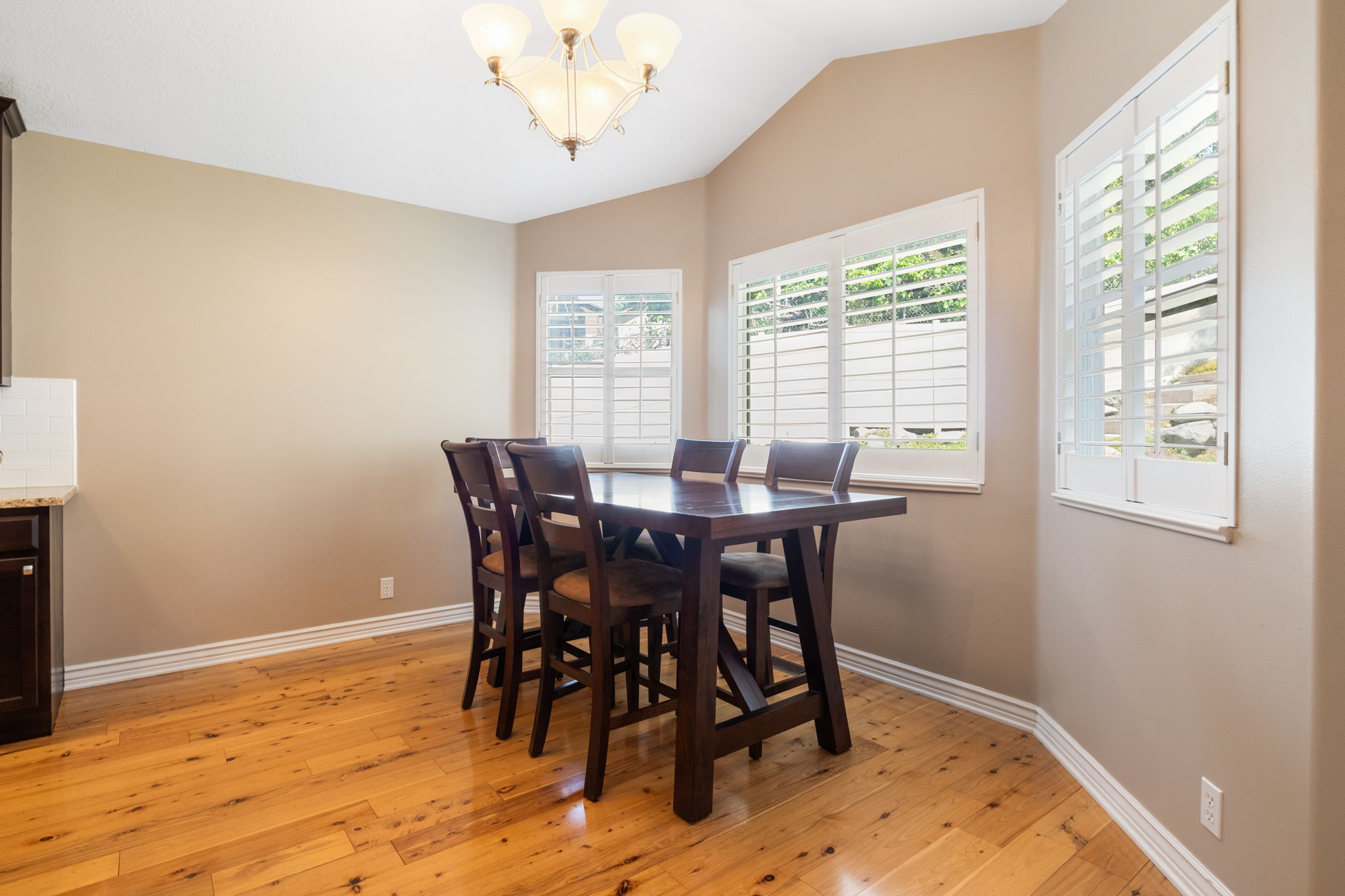 Dining space featuring wood-finish flooring, a vaulted ceiling, and a multi-light chandelier
