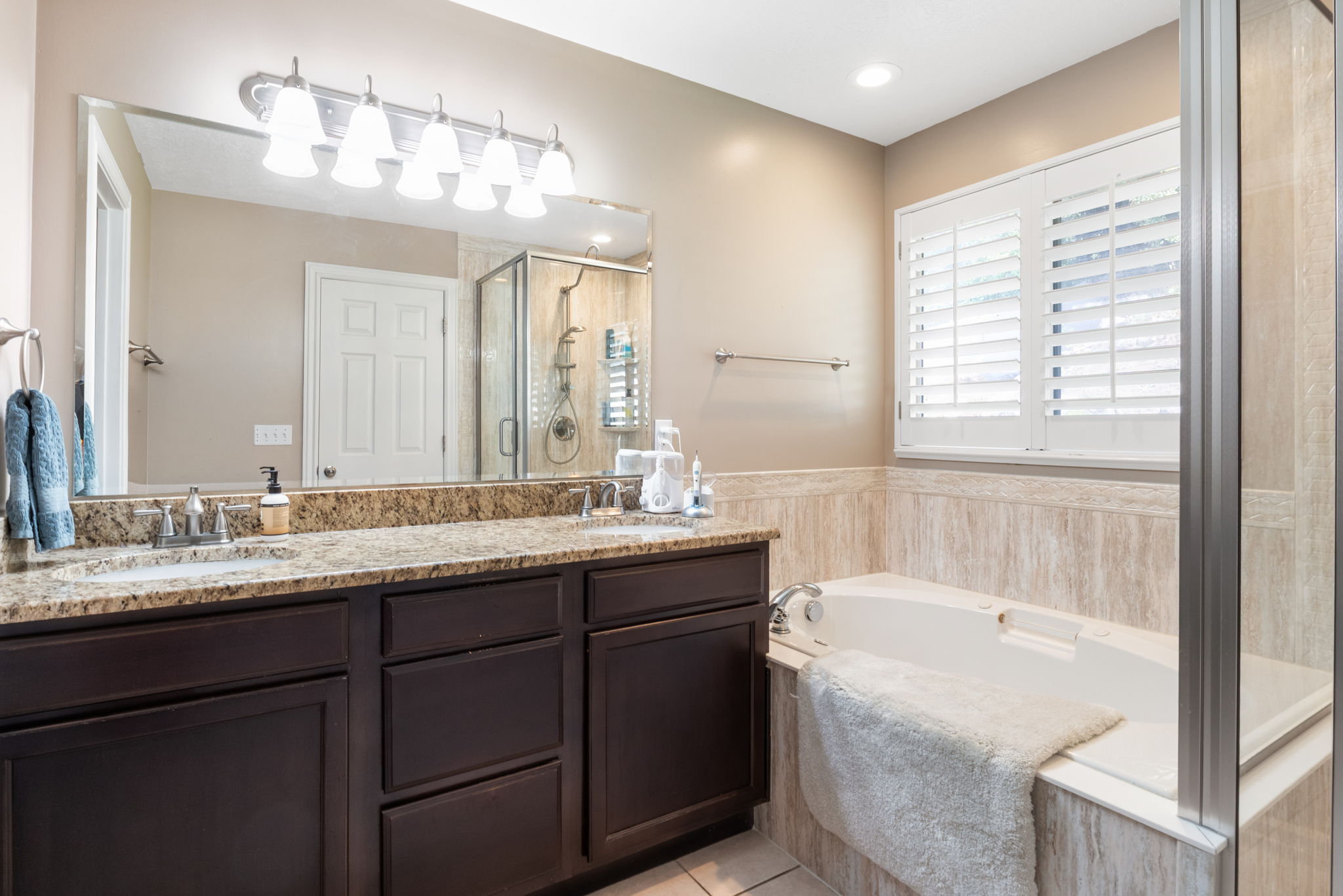 Dual vanity with a stone-finish countertop, undermount sinks, and dark wood cabinetry