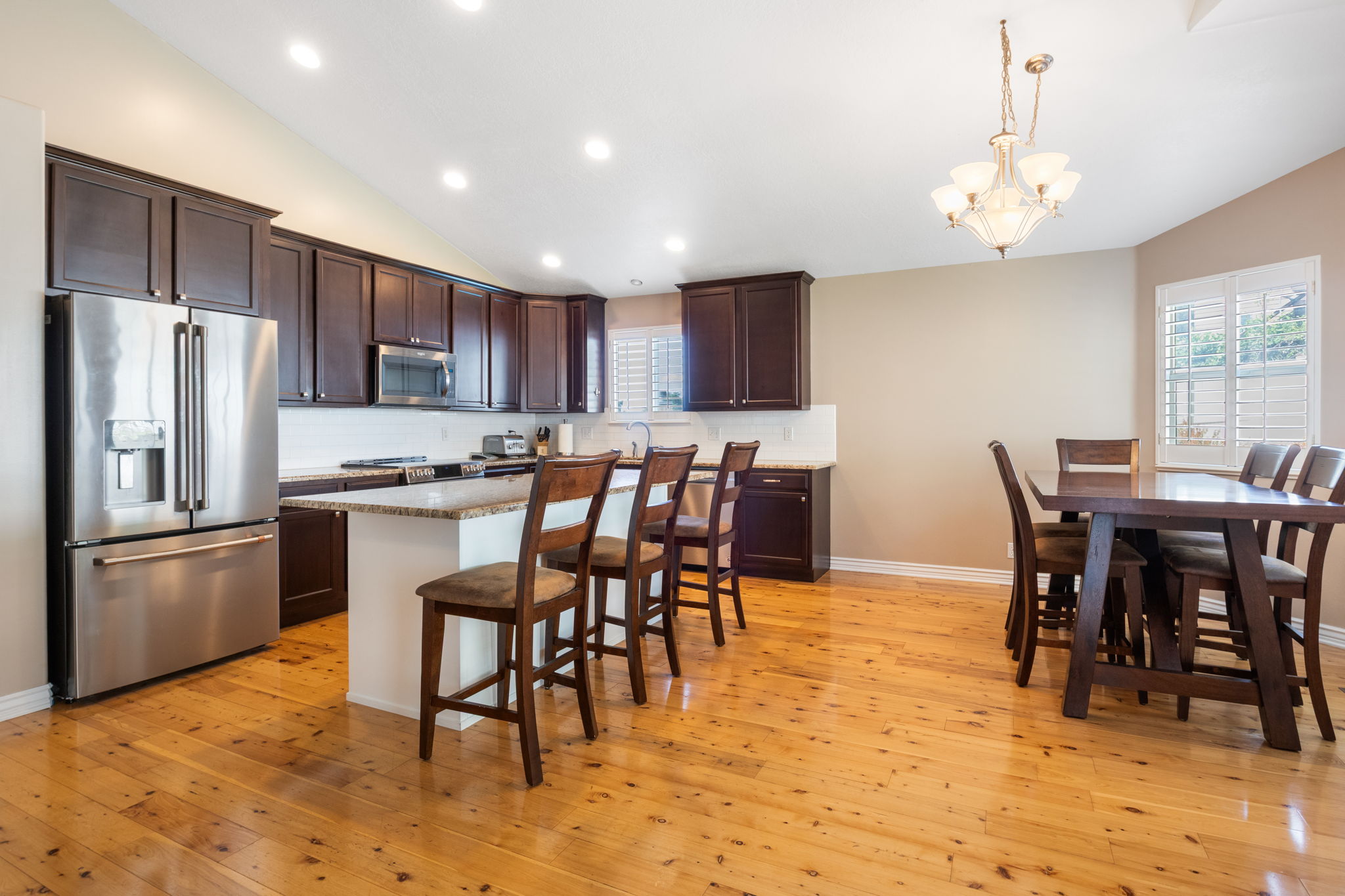 Kitchen and dining area featuring wood-finish flooring, dark wood cabinetry, and stainless steel appliances