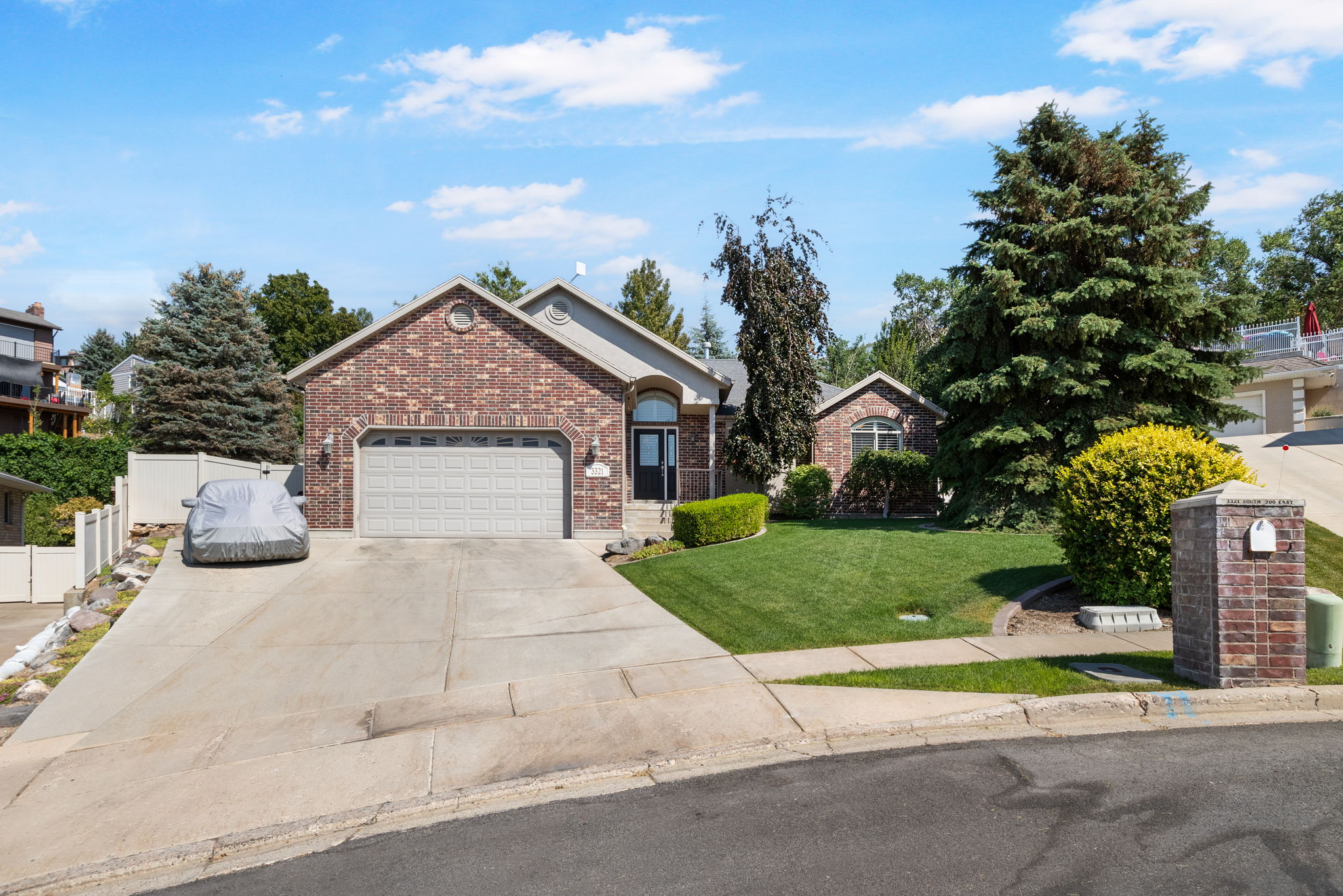 Brick-front residence featuring a two-car garage, arched entry, and a pitched roofline