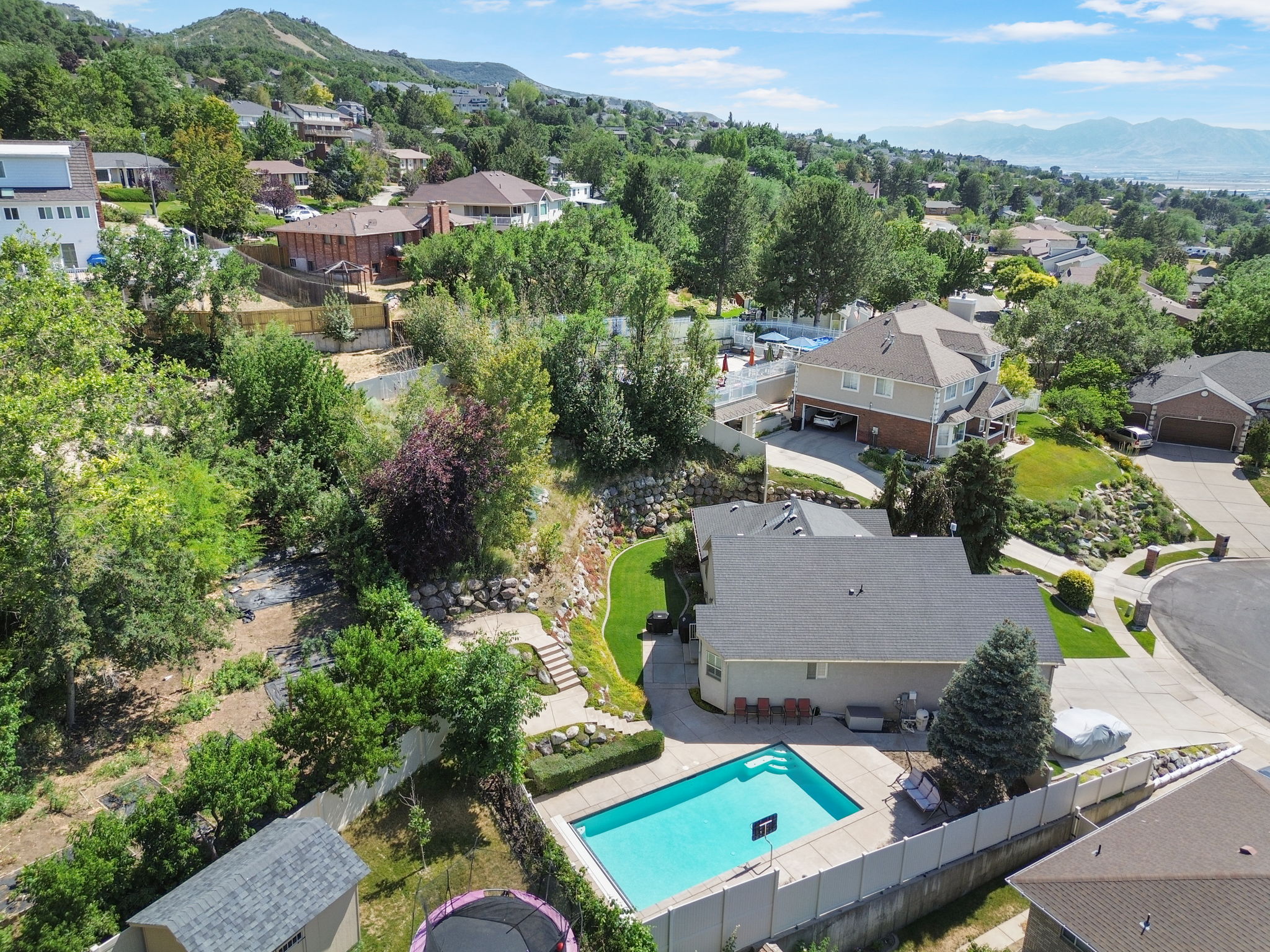 Aerial property view showcasing a private swimming pool, surrounding paved patio, and a privacy fence