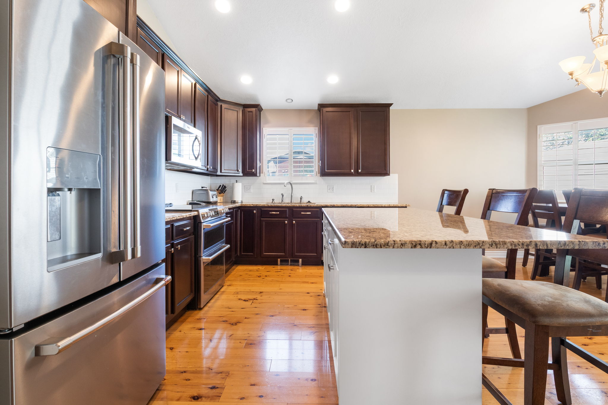 Kitchen featuring stainless steel appliances, dark wood cabinetry, and light wood-finish flooring