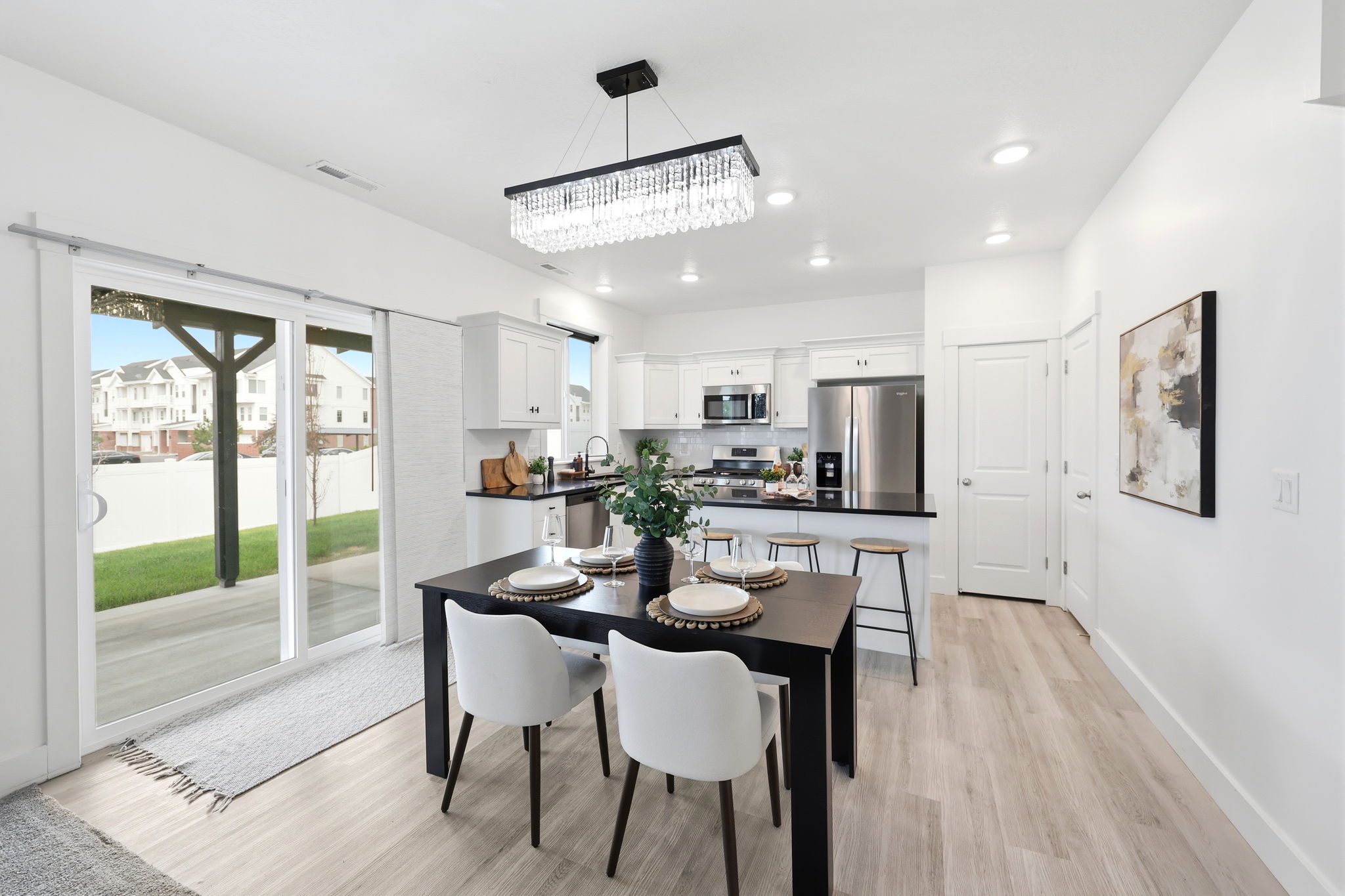 Open-concept dining area featuring light wood-finish flooring, a contemporary chandelier, and recessed lighting