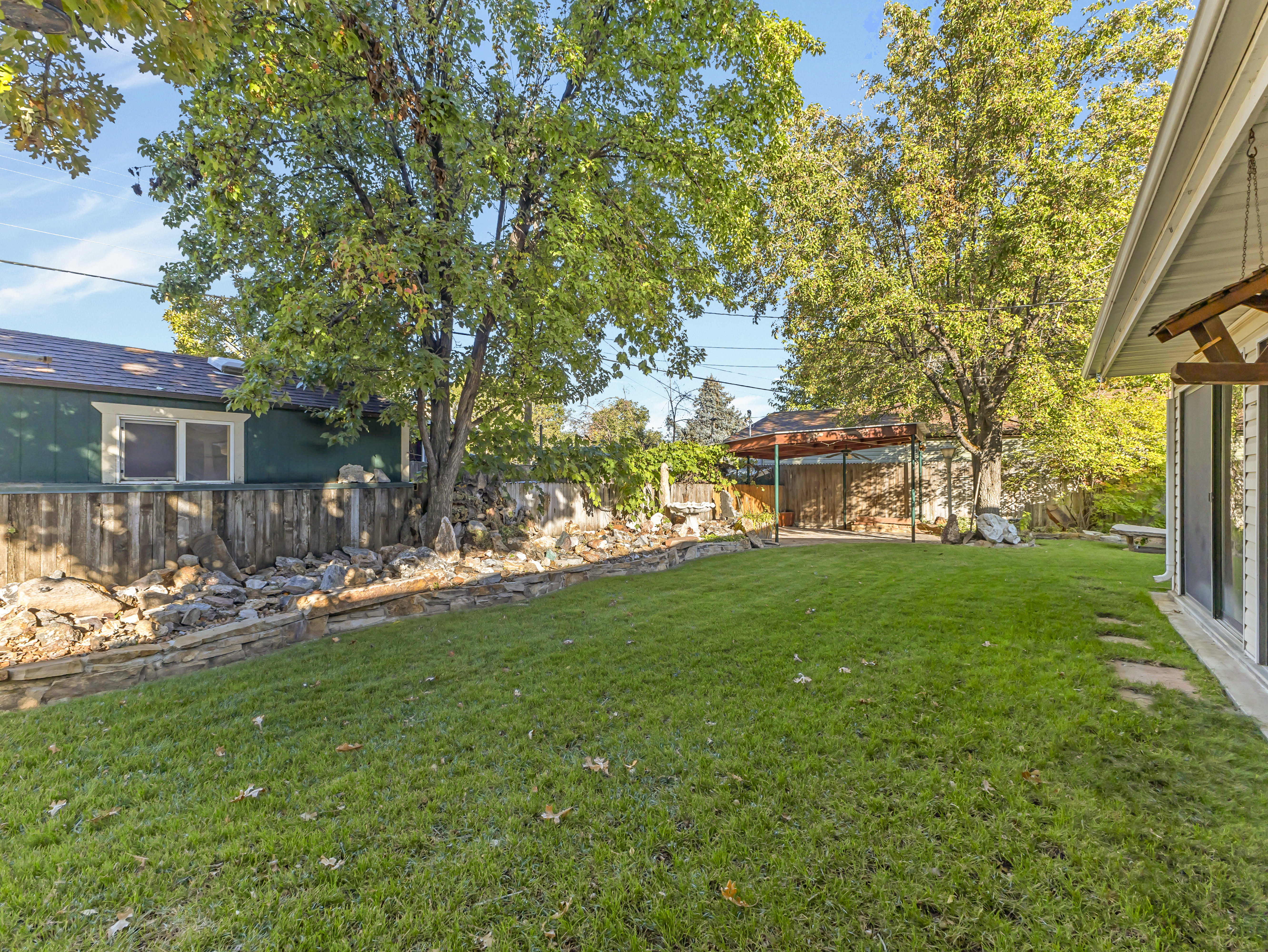 Expansive green lawn with mature trees and a stone retaining wall