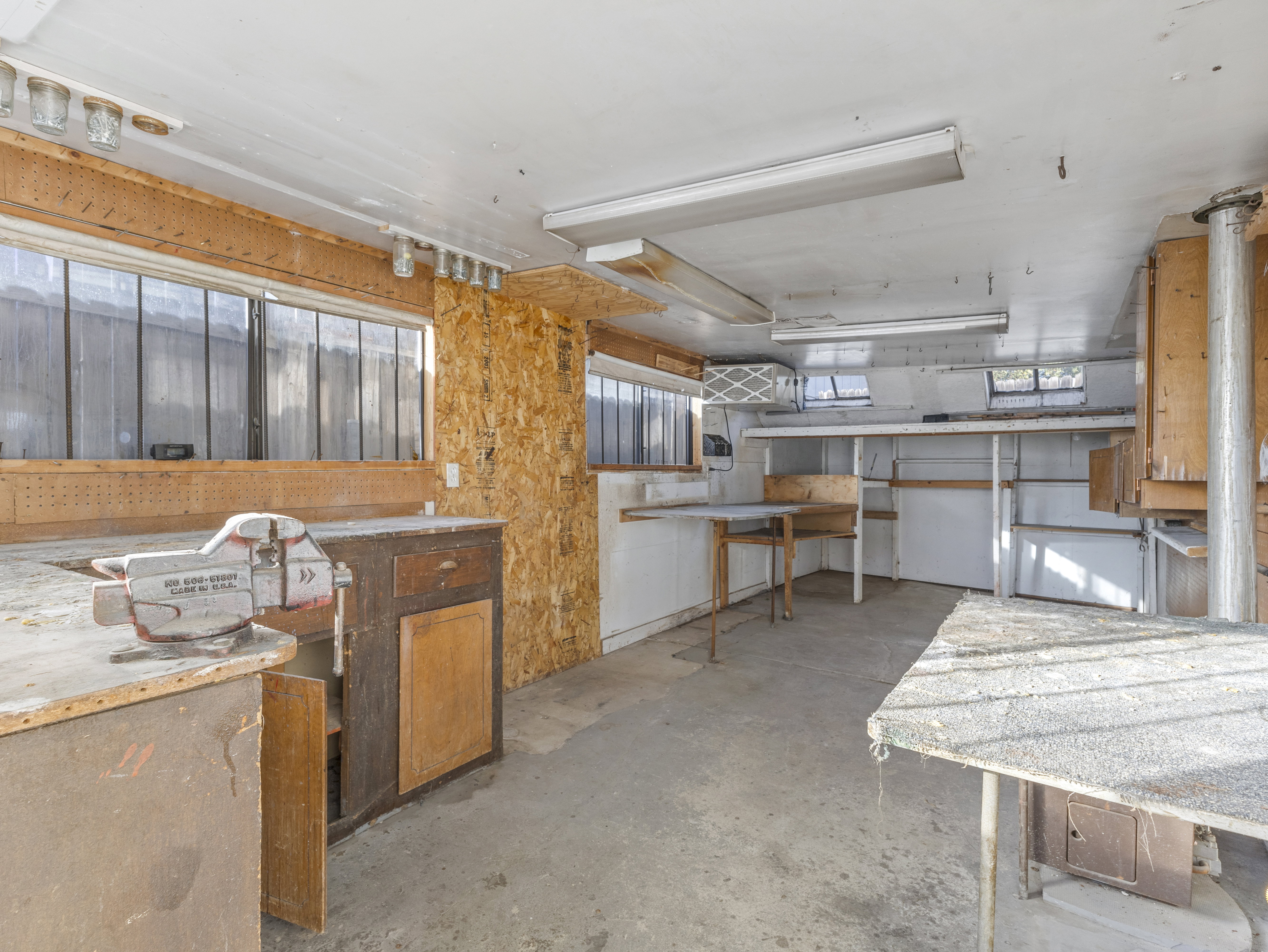 Utility space featuring a concrete floor, built-in shelving, multiple windows, and fluorescent lighting fixtures