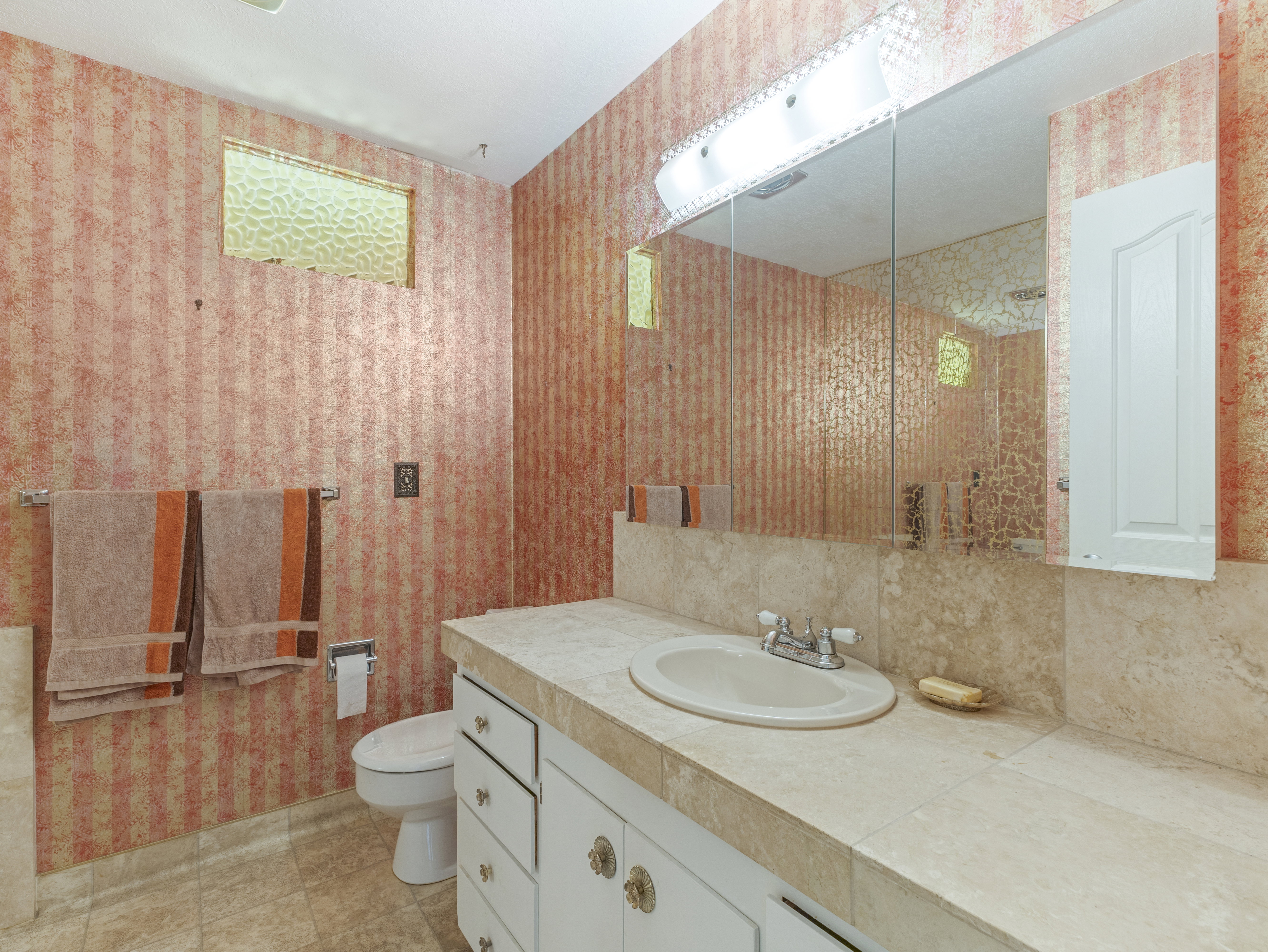 Bathroom featuring a vanity with a drop-in sink, a built-in medicine cabinet, and a large wall mirror