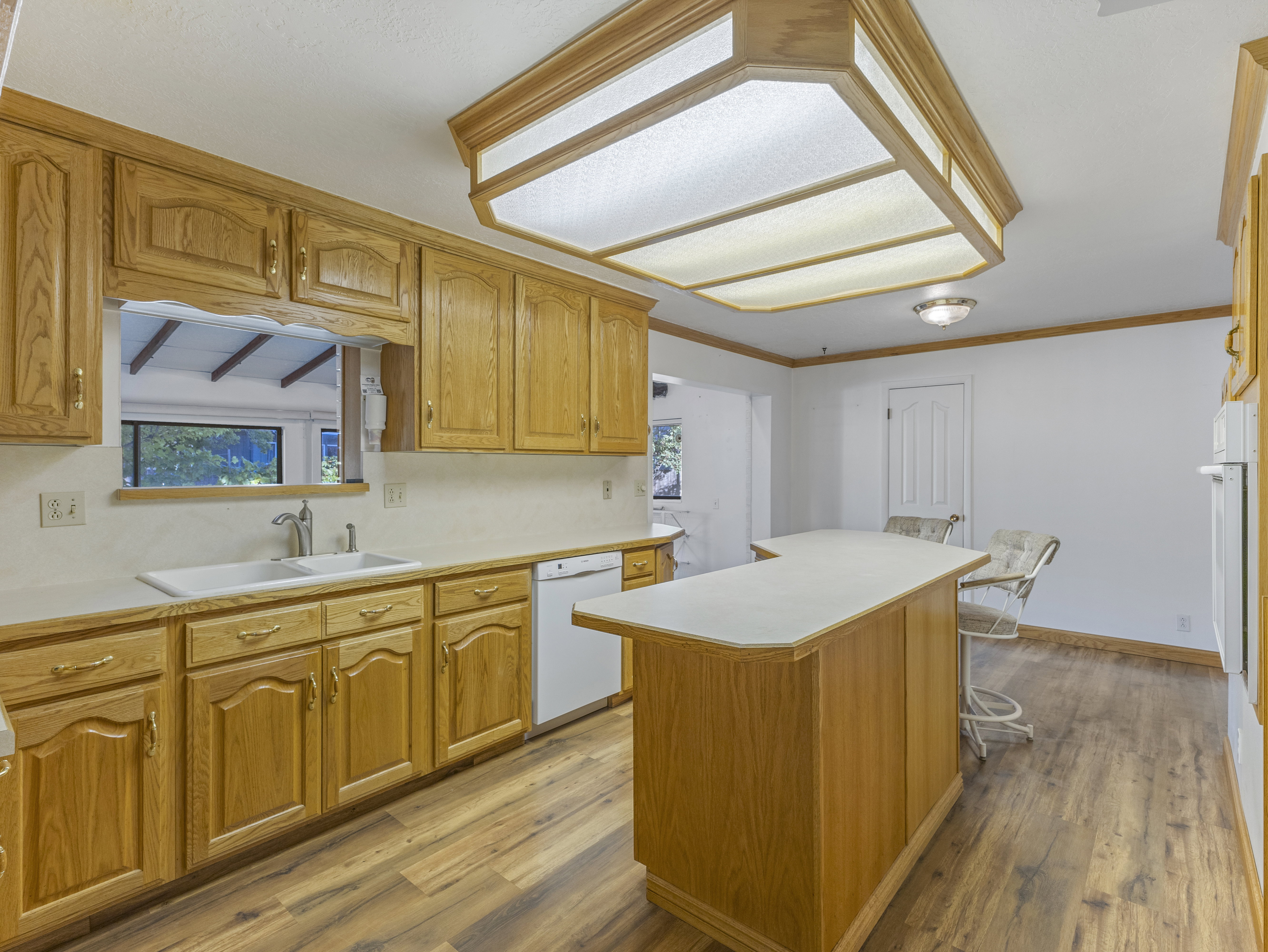 Kitchen featuring wood cabinetry, light countertops, wood-finish flooring, and a central island with seating