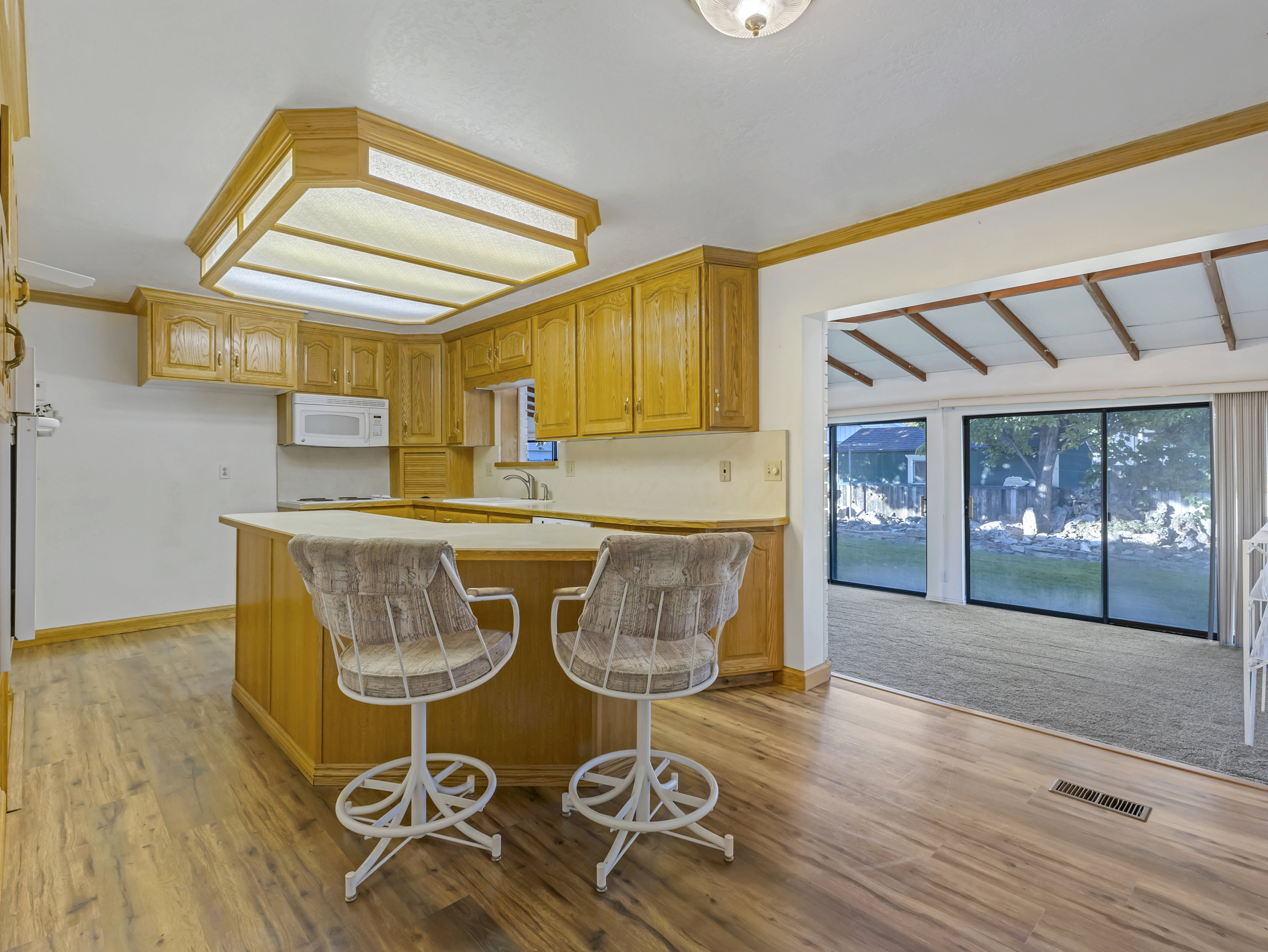 Kitchen featuring wood-finish flooring, wood cabinetry, white countertops, and a built-in microwave