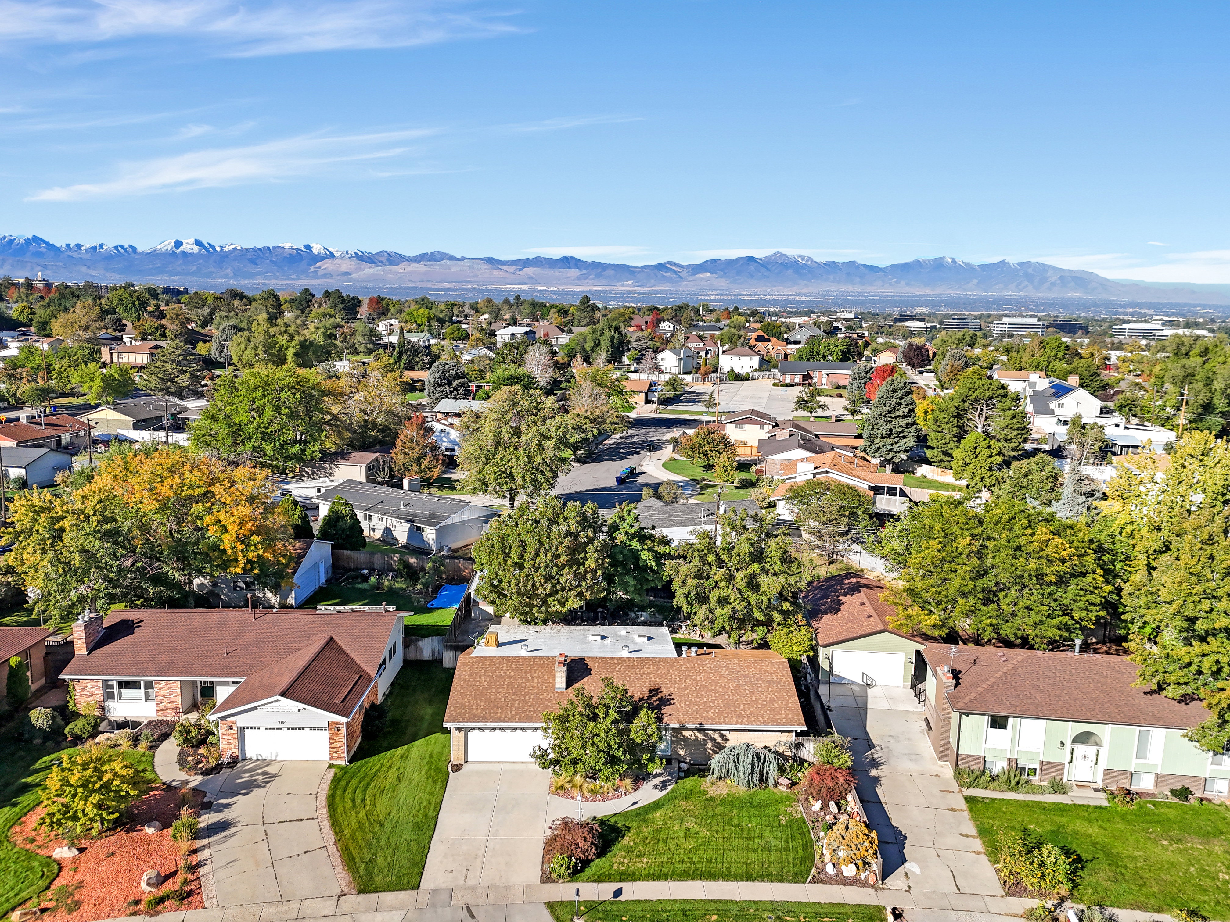 Expansive suburban neighborhood with mature trees and mountain scenery