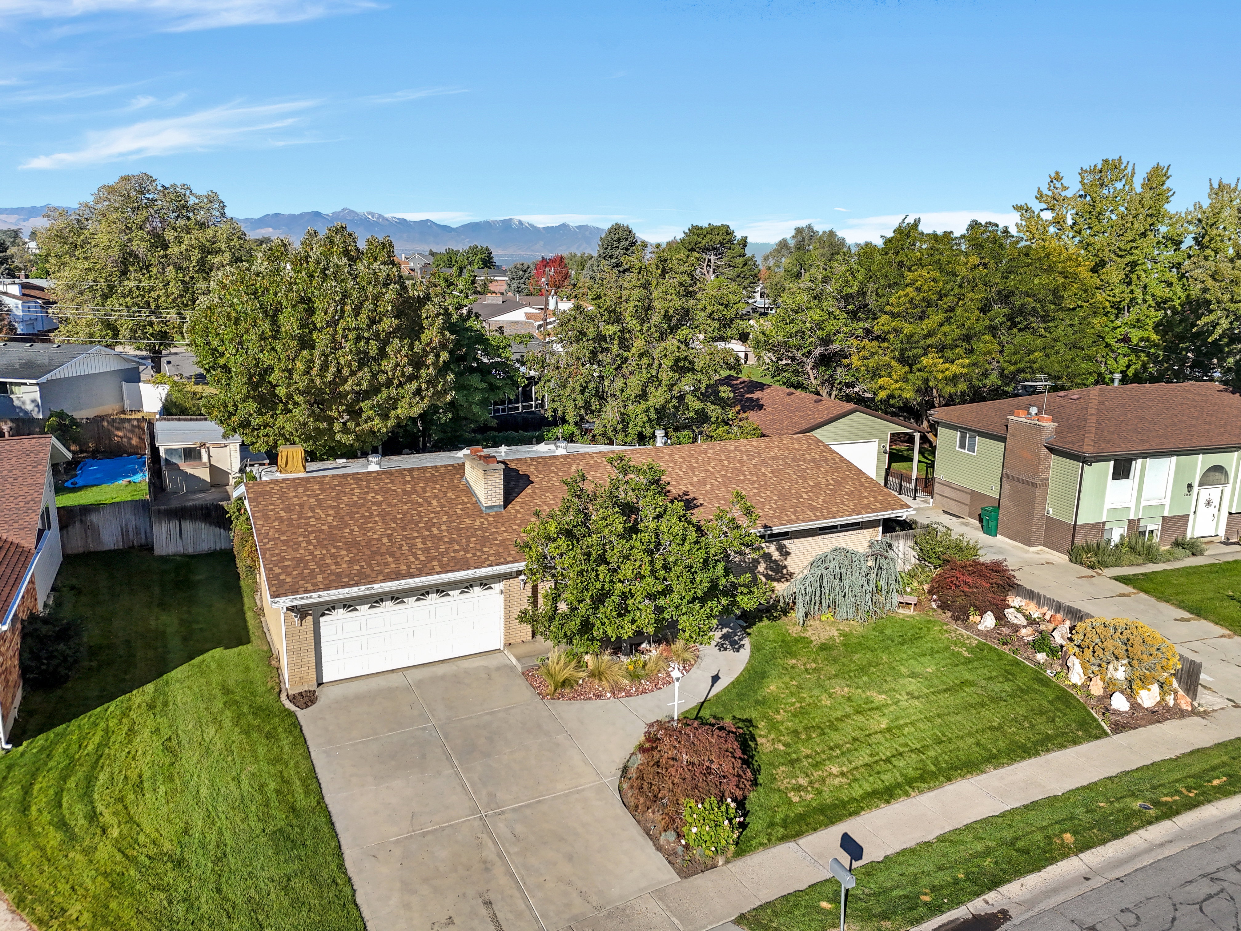 Ranch-style residence featuring a prominent brown shingle roof, a two-car garage with a white door, and a concrete driveway