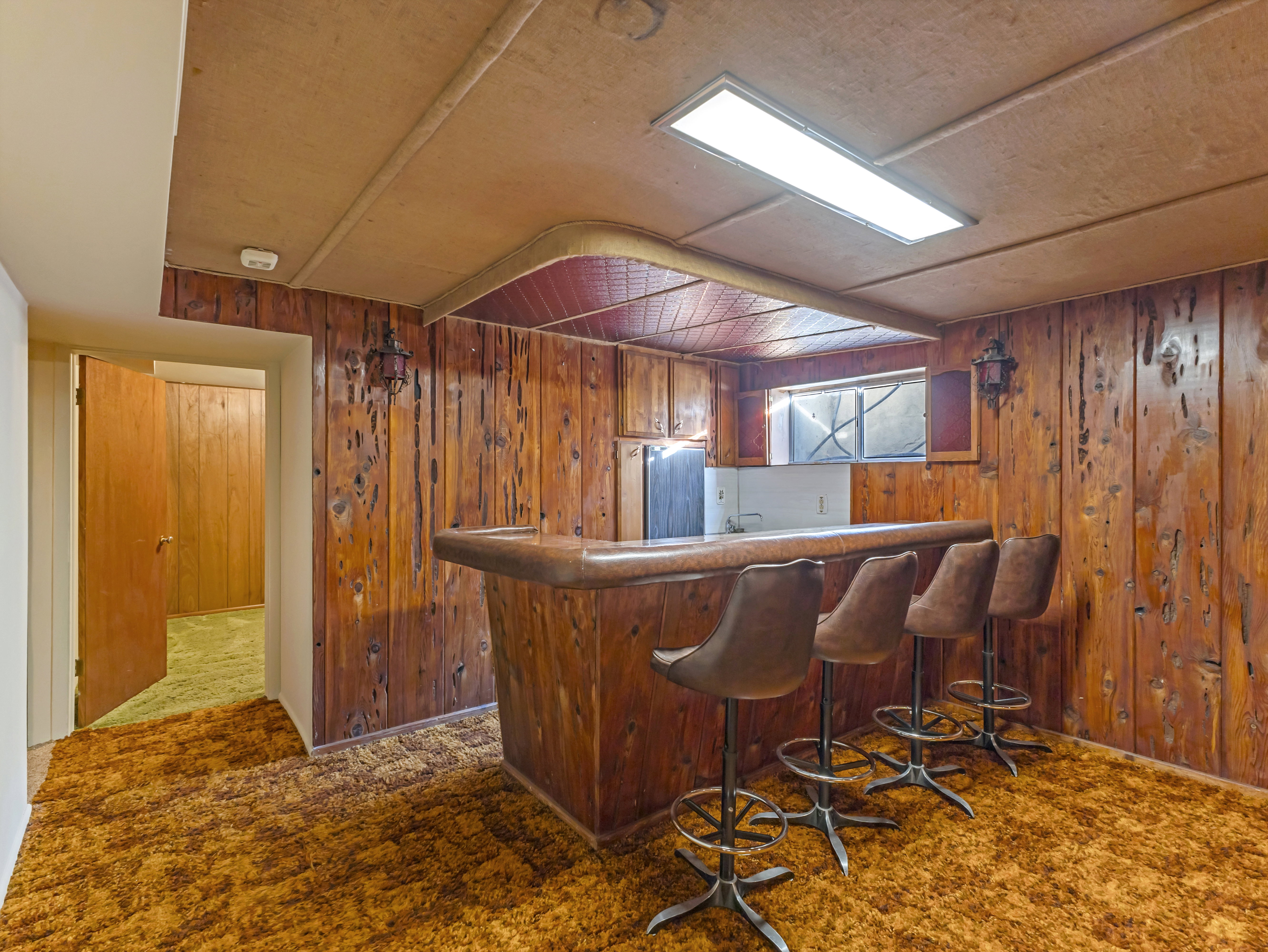 Recreation room featuring wood paneling, a built-in bar, and recessed lighting