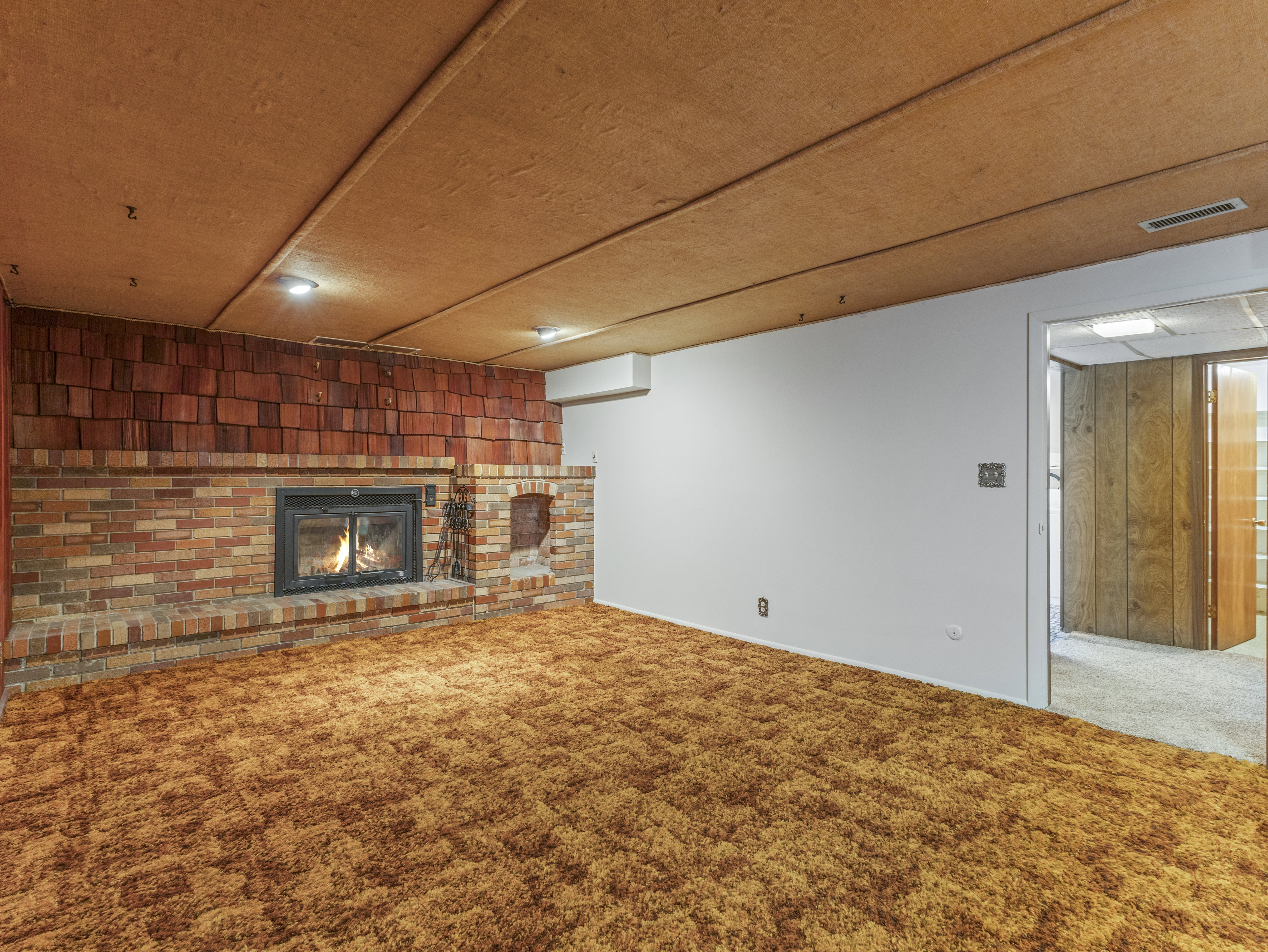 Brick fireplace with a metal insert, a brick hearth, and a shingle-style accent wall