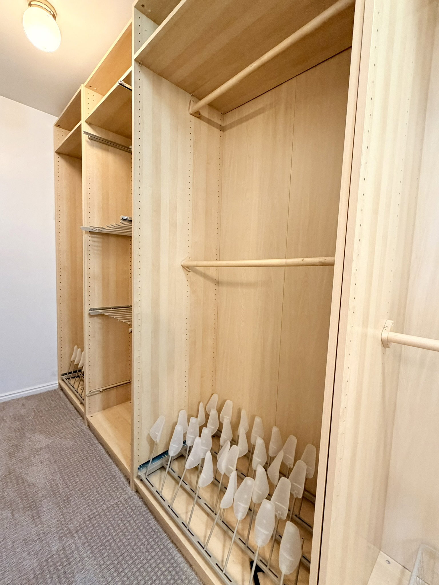 Custom closet system featuring light wood-finish cabinetry in primary bedroom