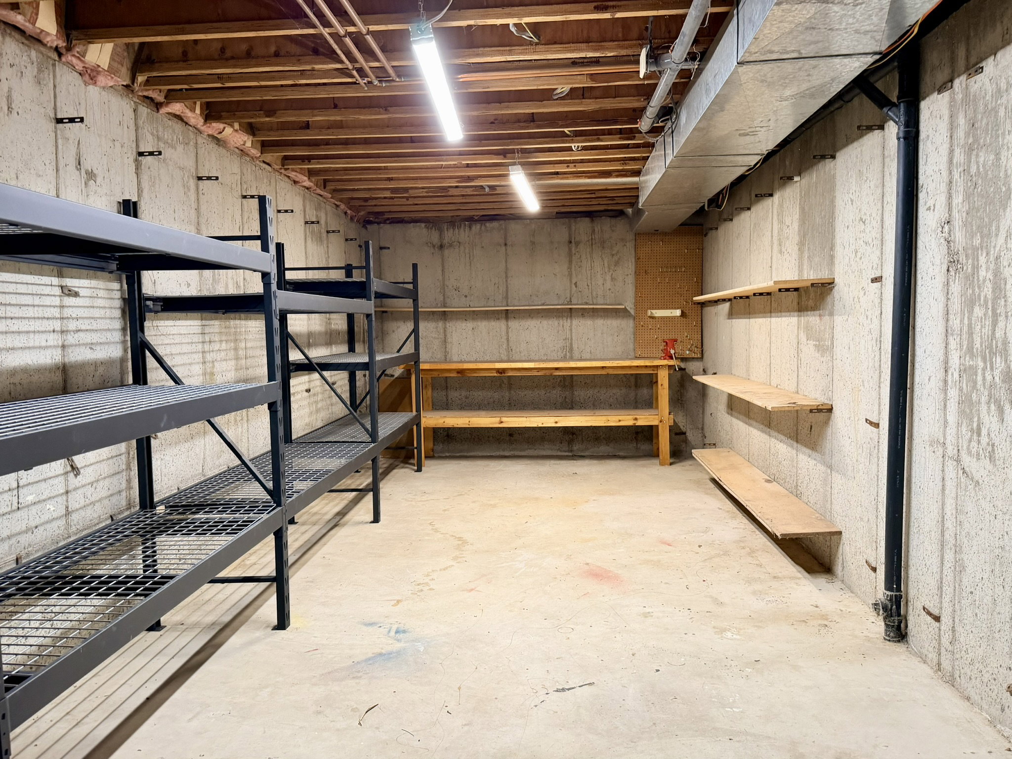 Unfinished basement featuring concrete walls, exposed ceiling joists, and a concrete floor