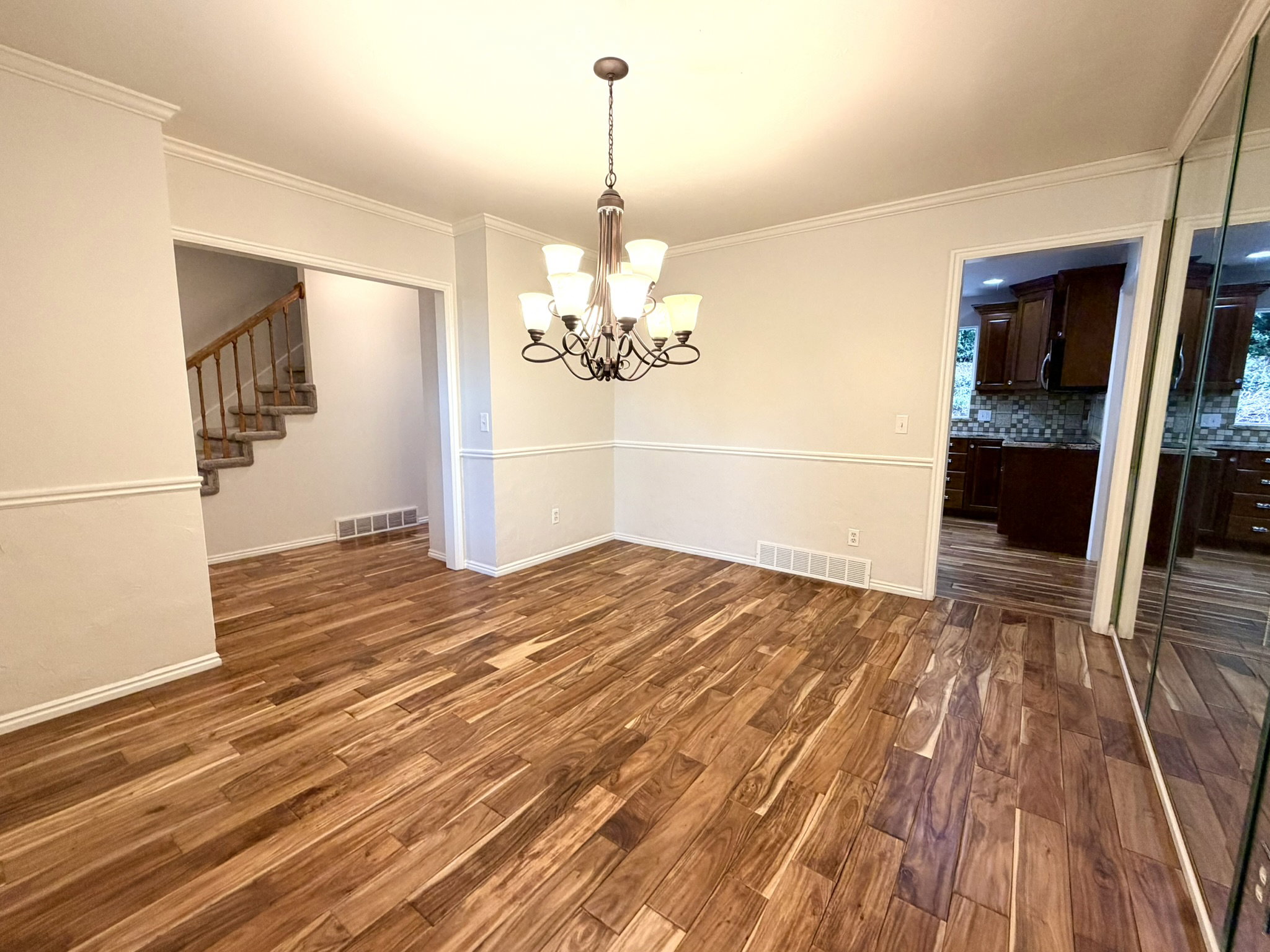 Spacious interior featuring wood-finish flooring, an ornate chandelier, and chair rail molding