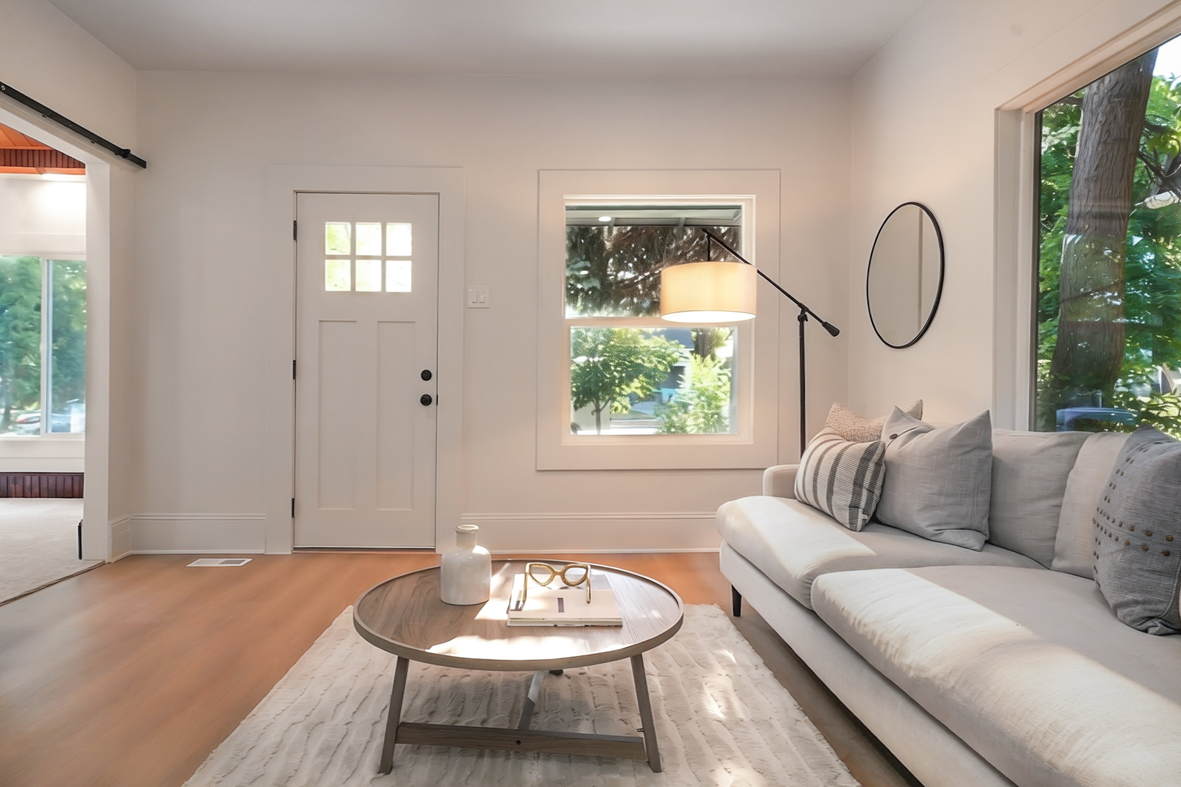 Bright living space featuring wood-finish flooring, white trim, and a white paneled door with windowpanes