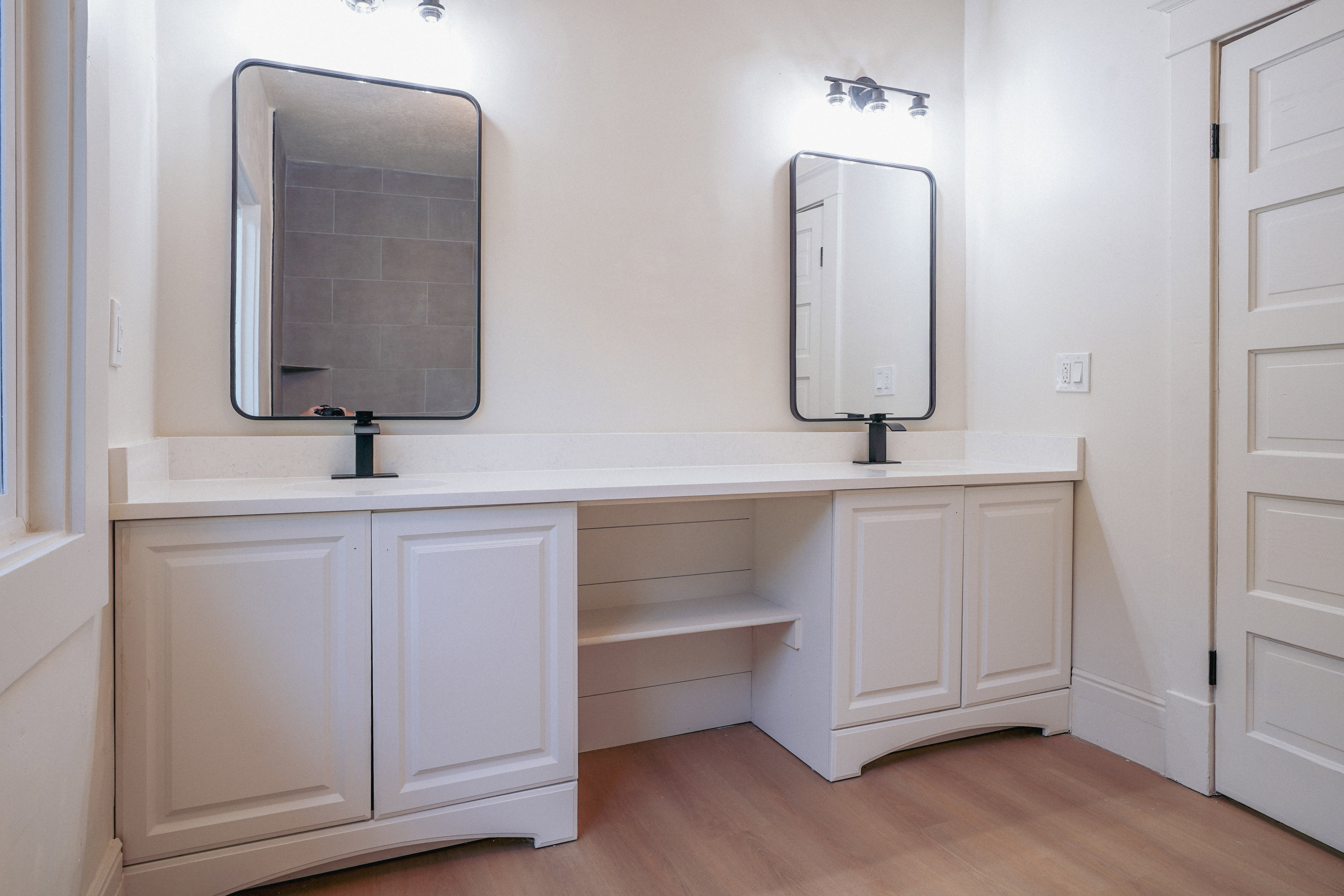 Dual vanity with white cabinetry, a light-toned countertop, and modern black framed mirrors