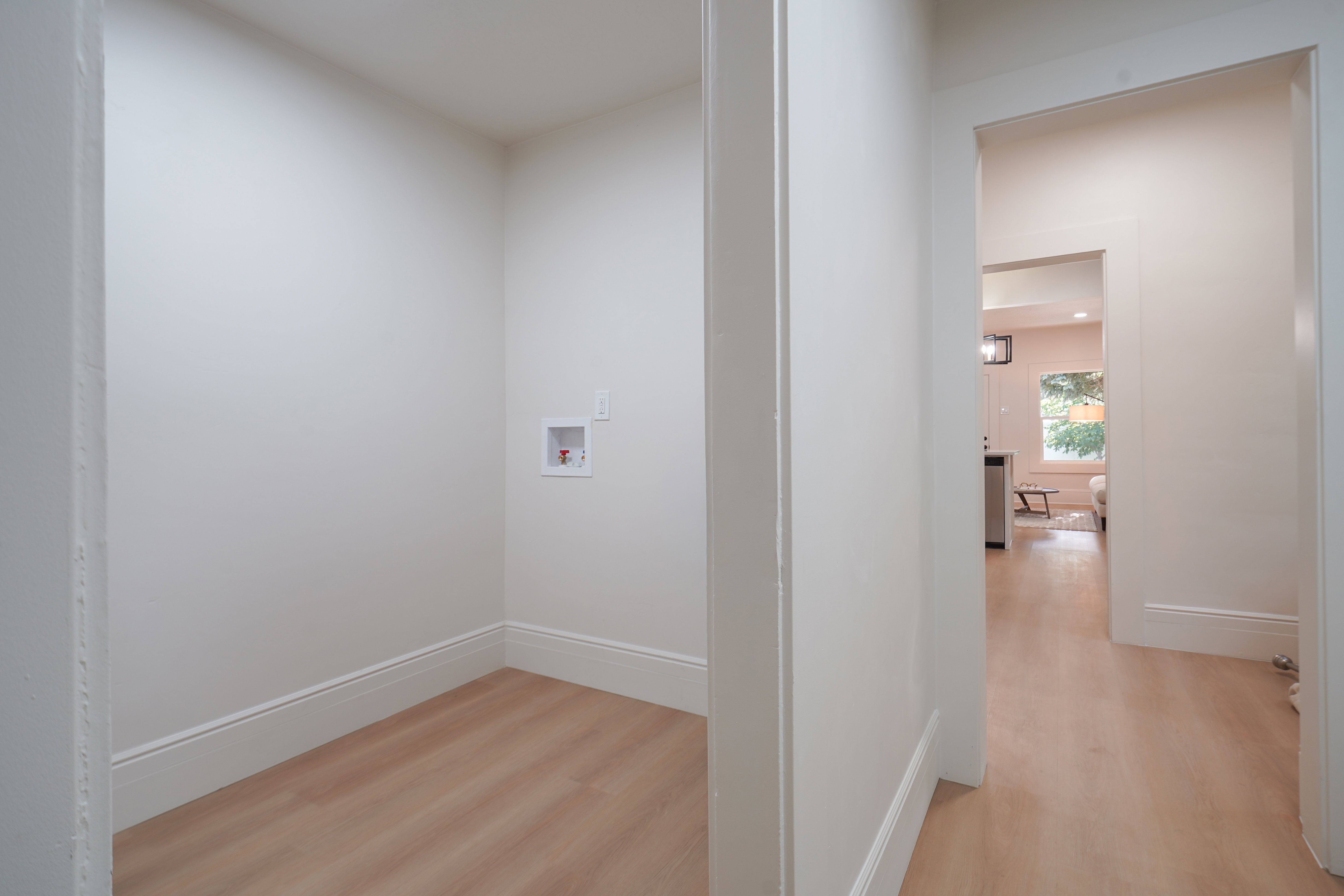 Dedicated laundry alcove with wall hookups, light wood-finish flooring, and crisp white baseboards