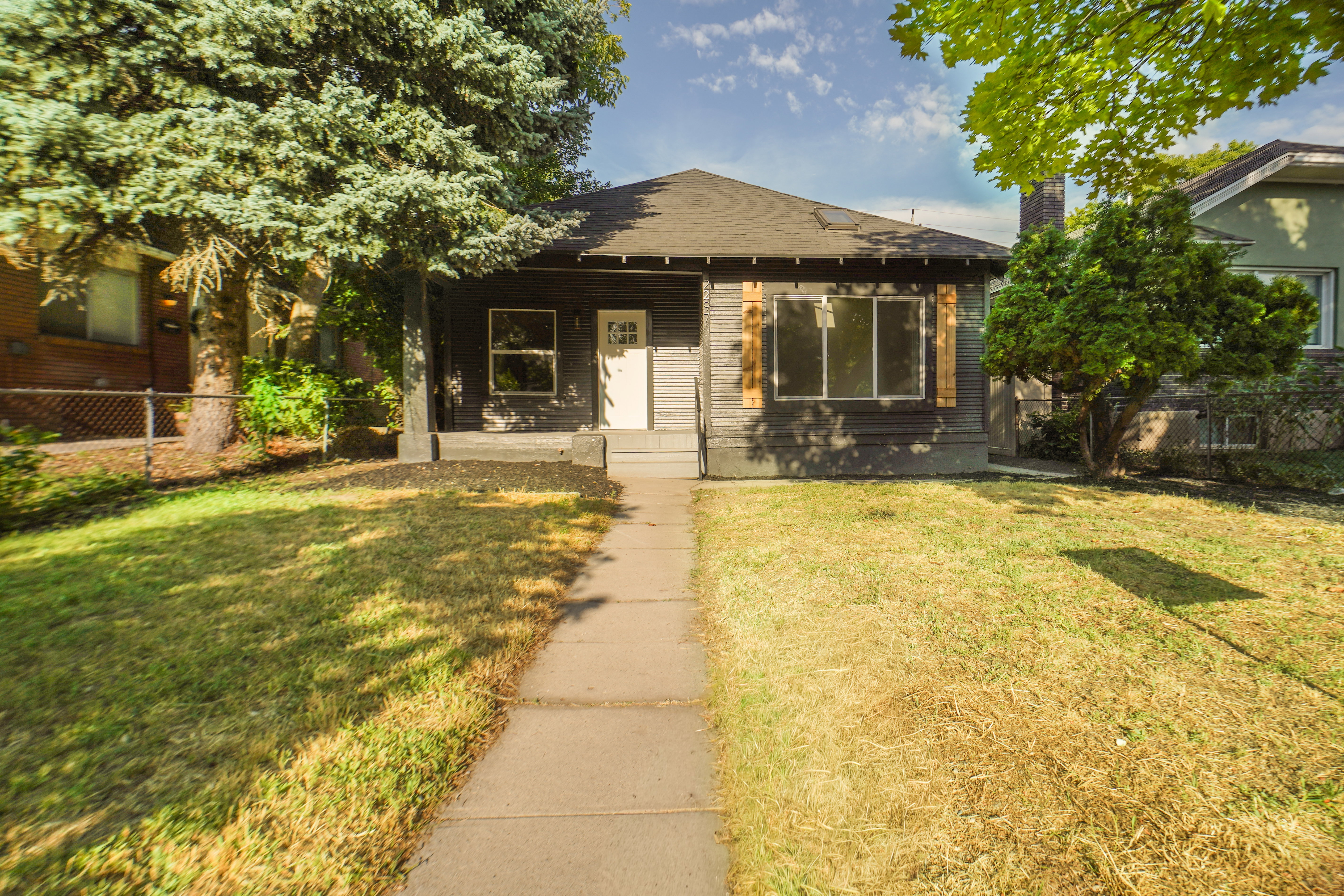 Single-story residence featuring dark siding, a white front door, and a covered porch entry