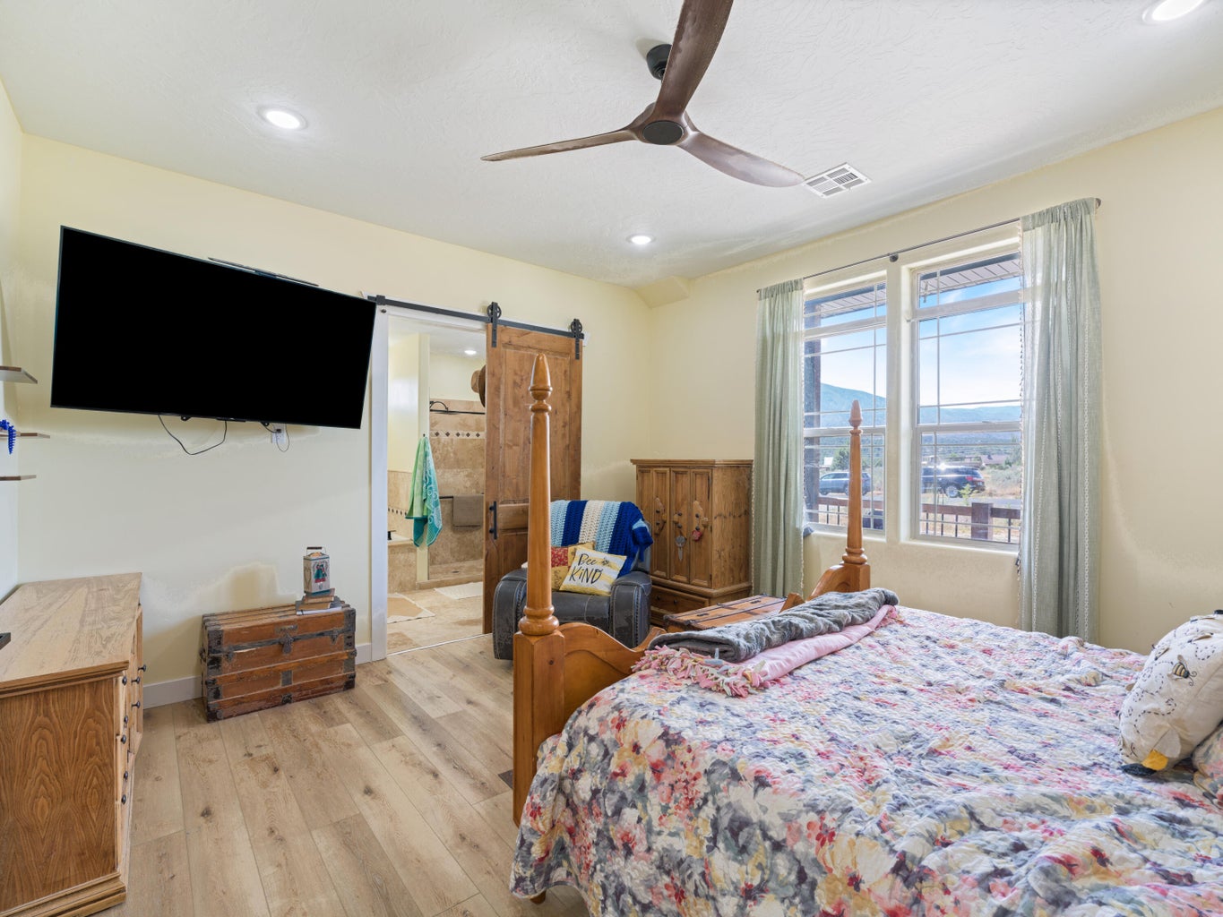 Spacious bedroom featuring wood-finish flooring and a ceiling fan