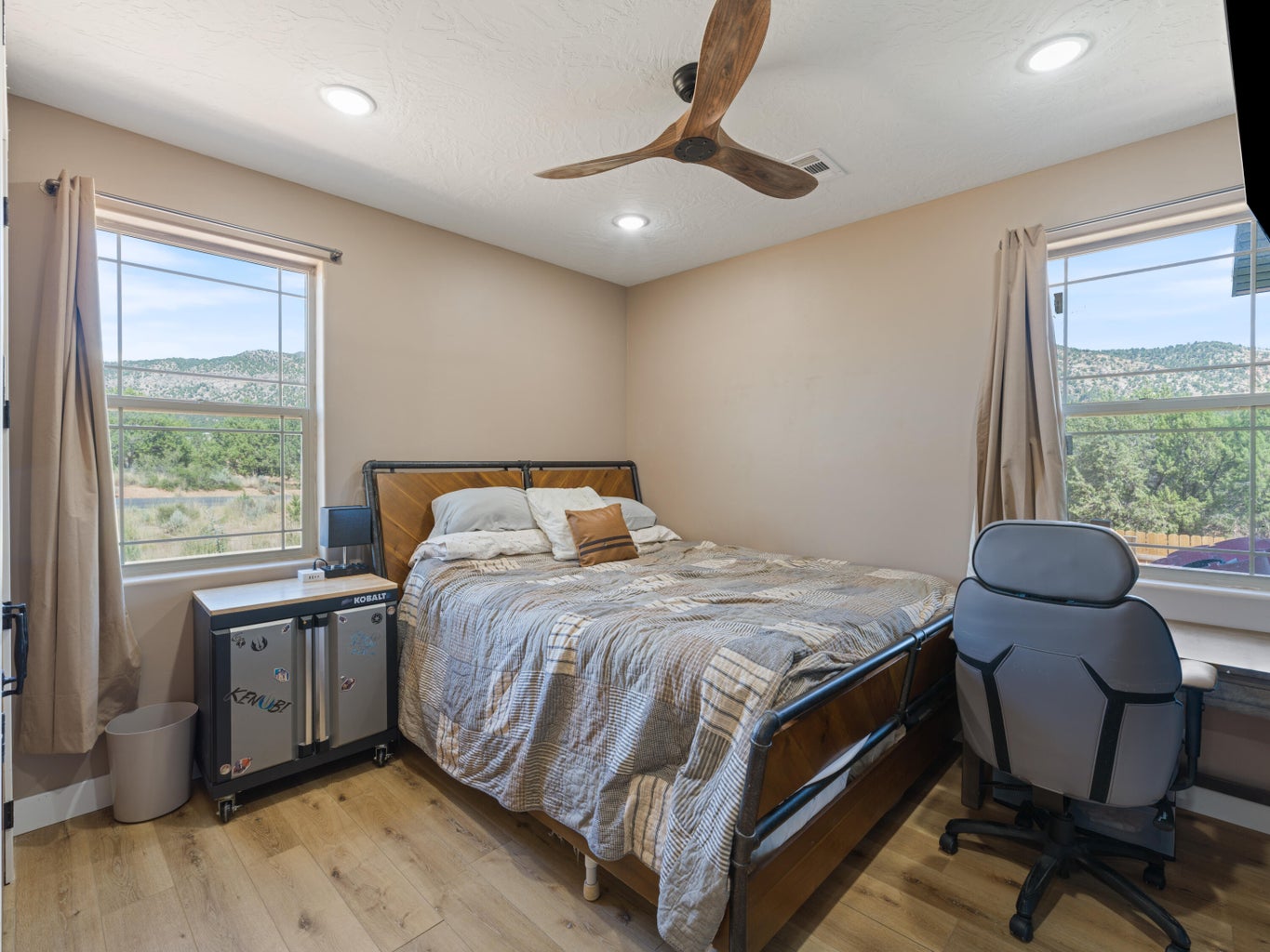 Spacious room featuring wood-finish flooring, two large windows, a ceiling fan with wood-look blades, and recessed lighting