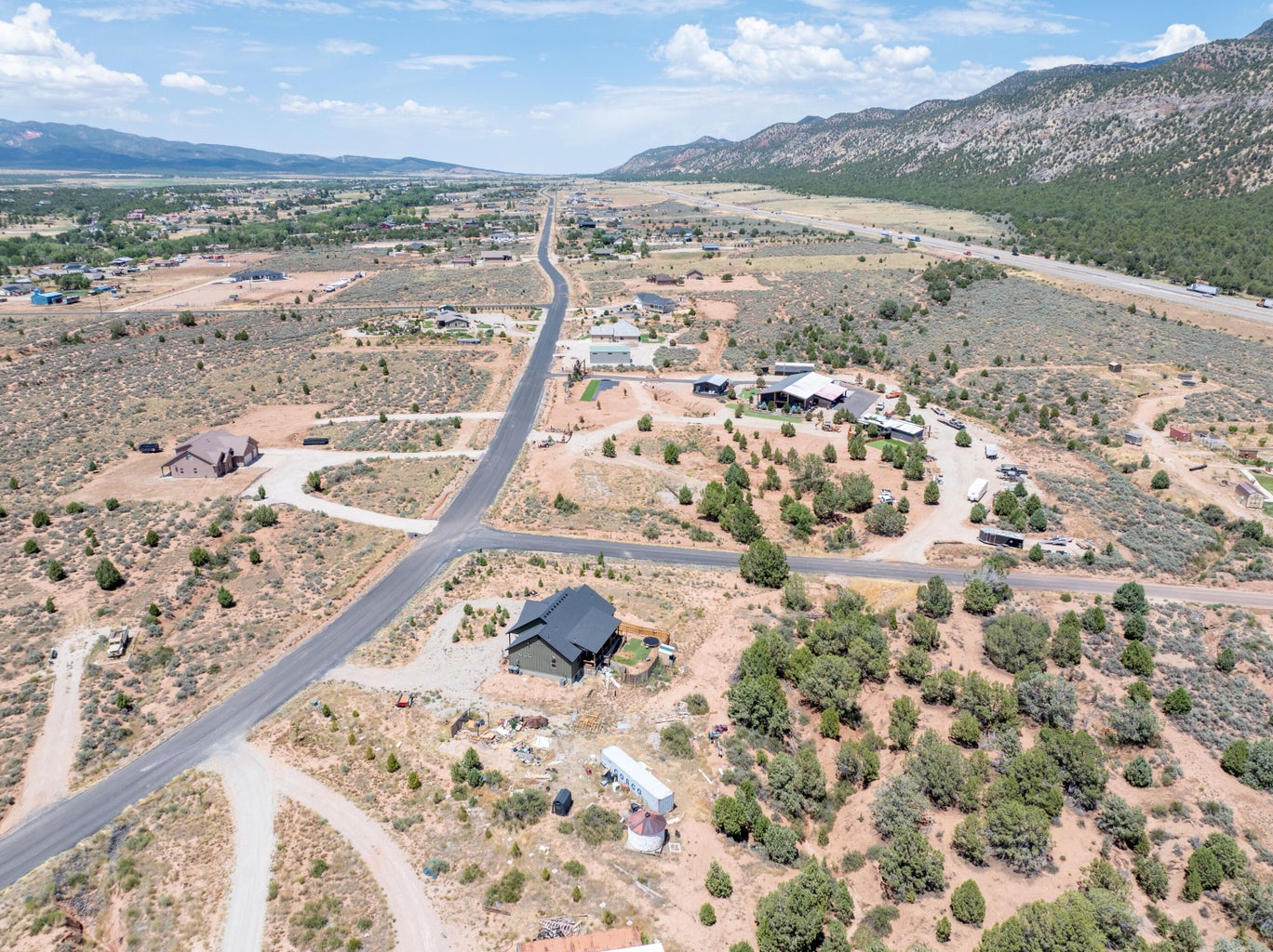 Expansive aerial landscape featuring a paved road, scattered residential properties, and natural desert vegetation