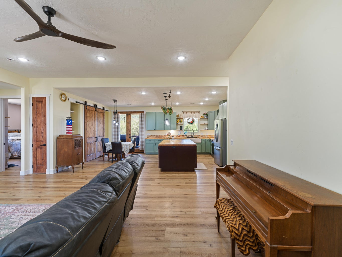 Open-concept living area with wood-finish flooring, recessed lighting, and a modern ceiling fan