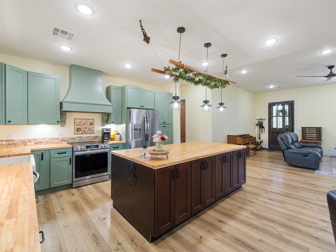 Kitchen featuring sage green cabinetry, stainless steel appliances, and wood-finish flooring