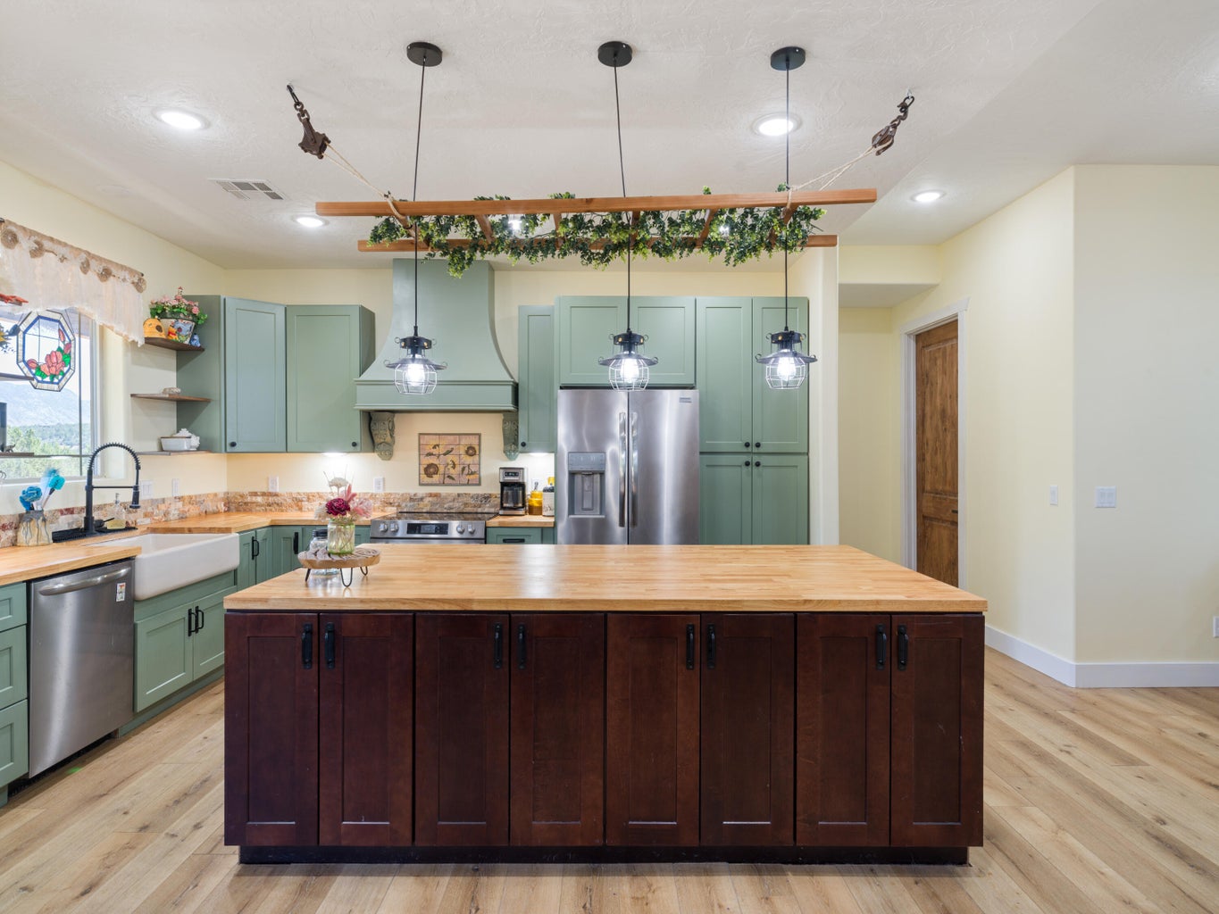 Kitchen featuring a large central island with a wood-finish countertop and dark wood cabinetry