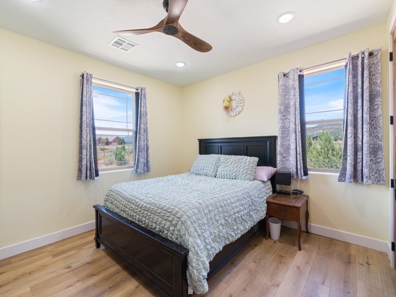 Interior room featuring wood-finish flooring, two large windows with exterior scenery, a ceiling fan with integrated lighting, and recessed ceiling lights