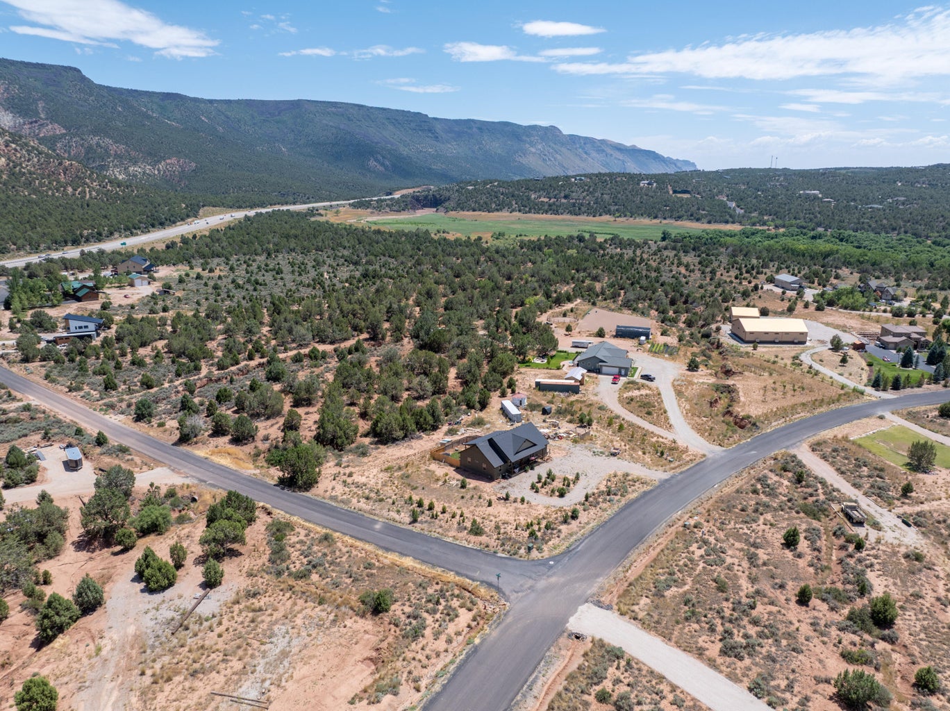 Expansive property with a modern home featuring a dark roof, surrounded by natural desert landscaping and scattered trees