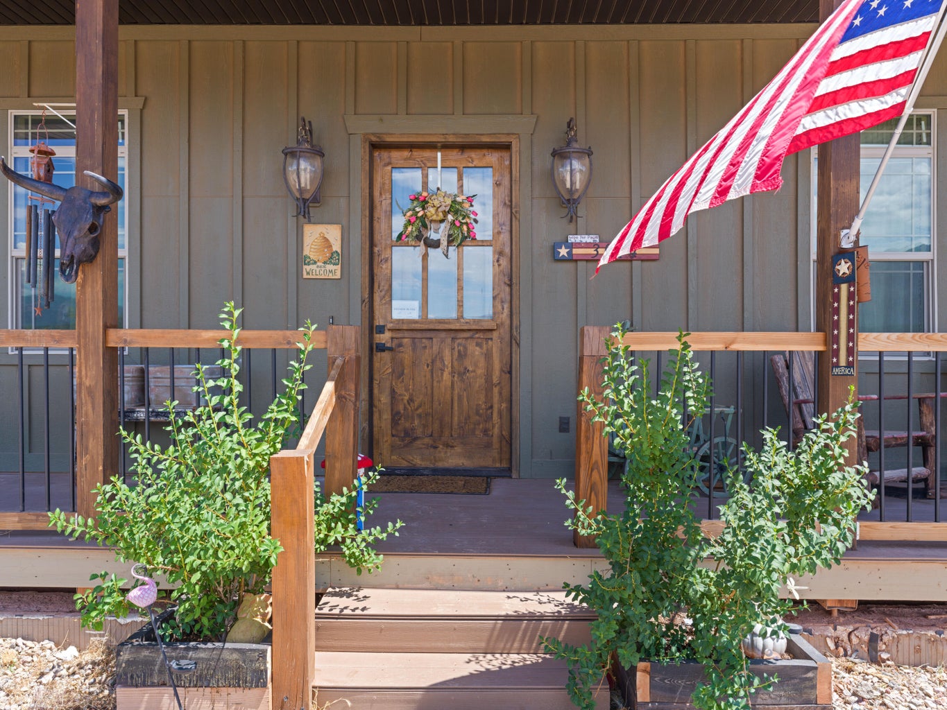Front entry featuring a paneled wood door with multi-pane glass, two exterior sconces, and a board and batten facade