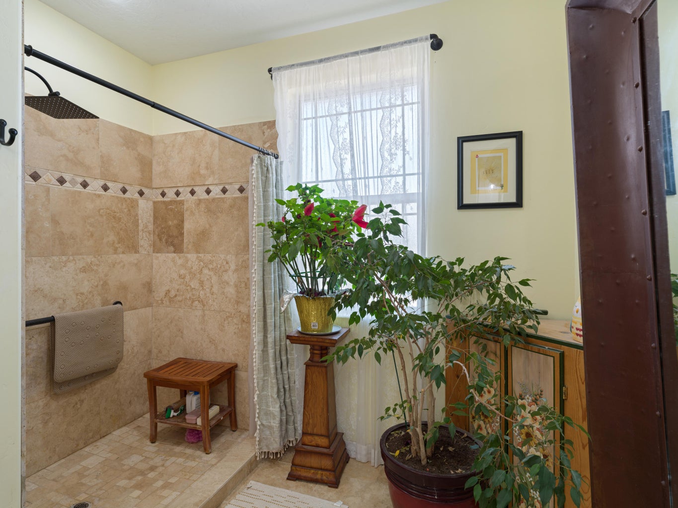 Tiled shower enclosure featuring a decorative accent band and integrated bench