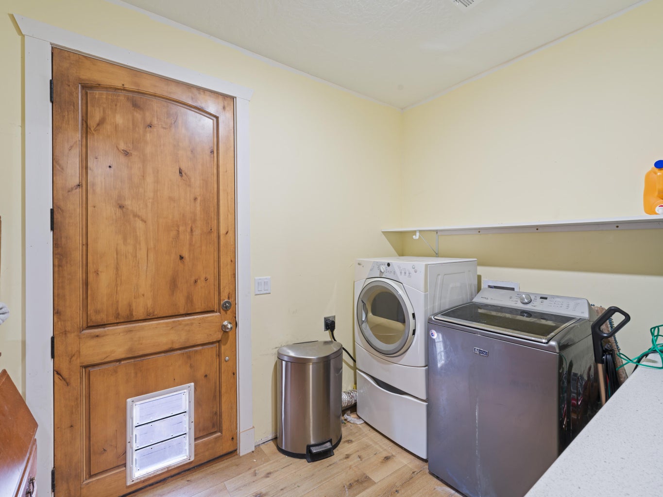 Laundry area featuring a wood-finish door with white trim, light-toned walls, and wood-finish flooring