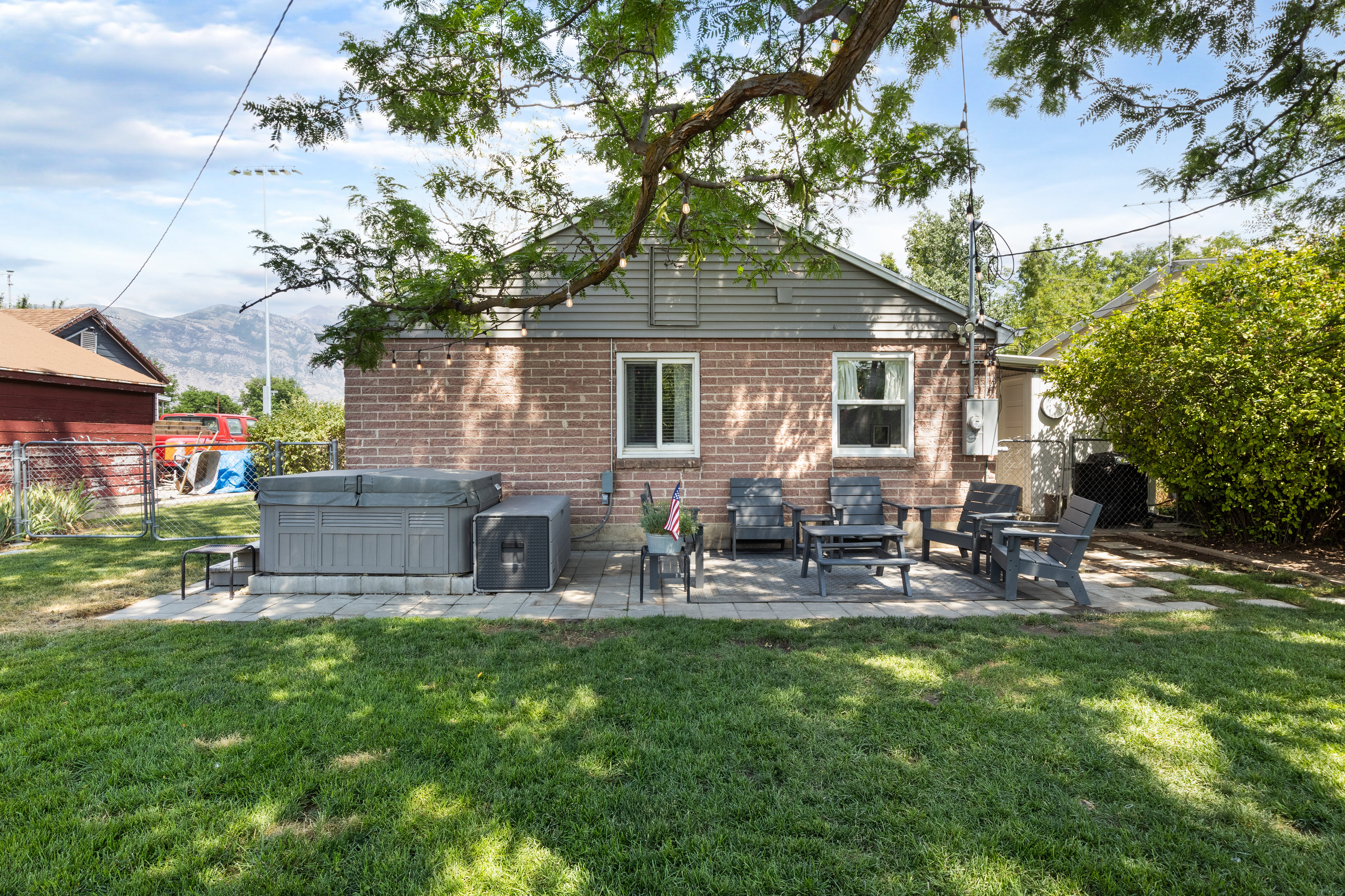 Expansive backyard featuring a brick exterior, paver patio, established tree, and distant mountain scenery