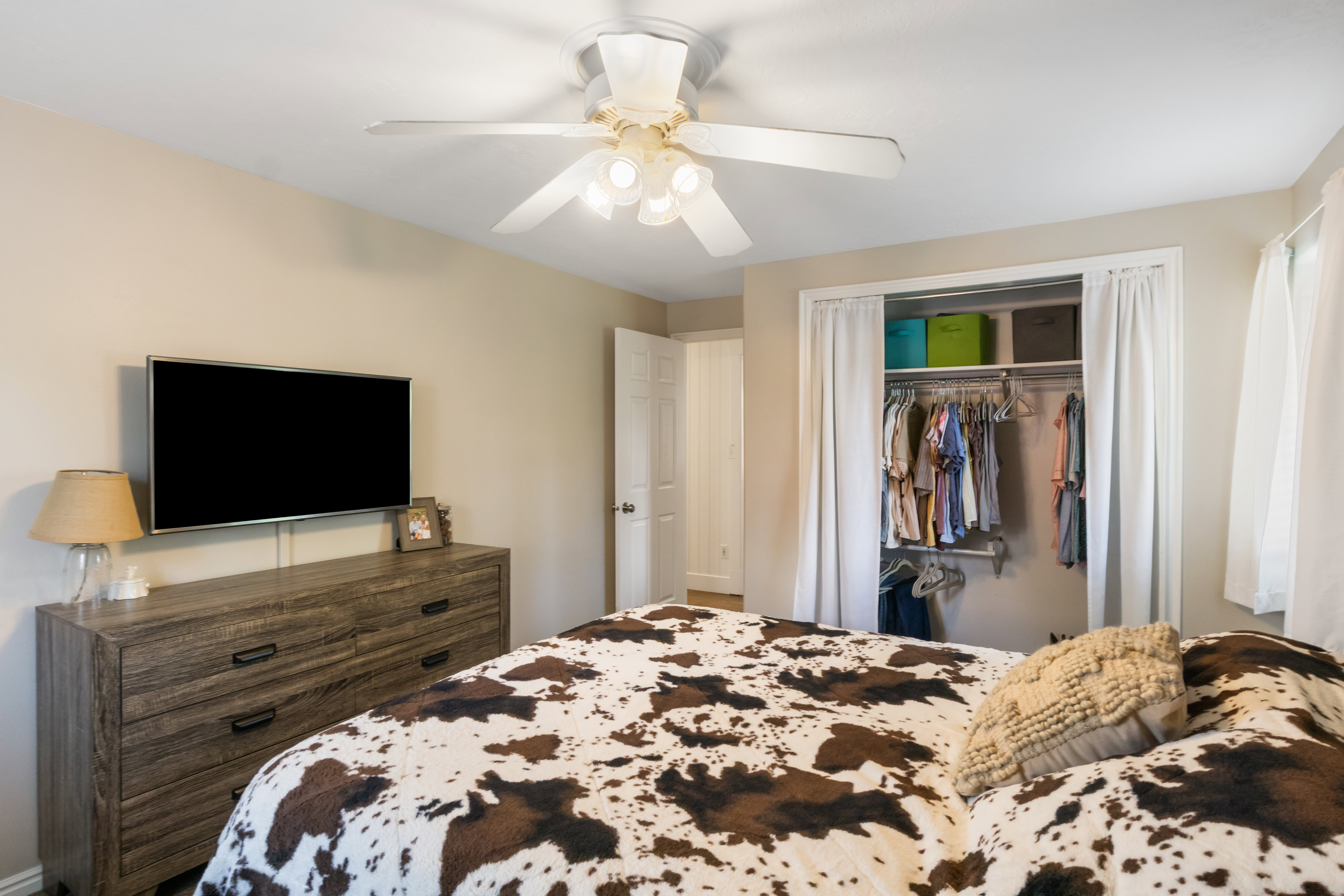 Recessed closet with curtain entry, overhead shelving, and hanging rods