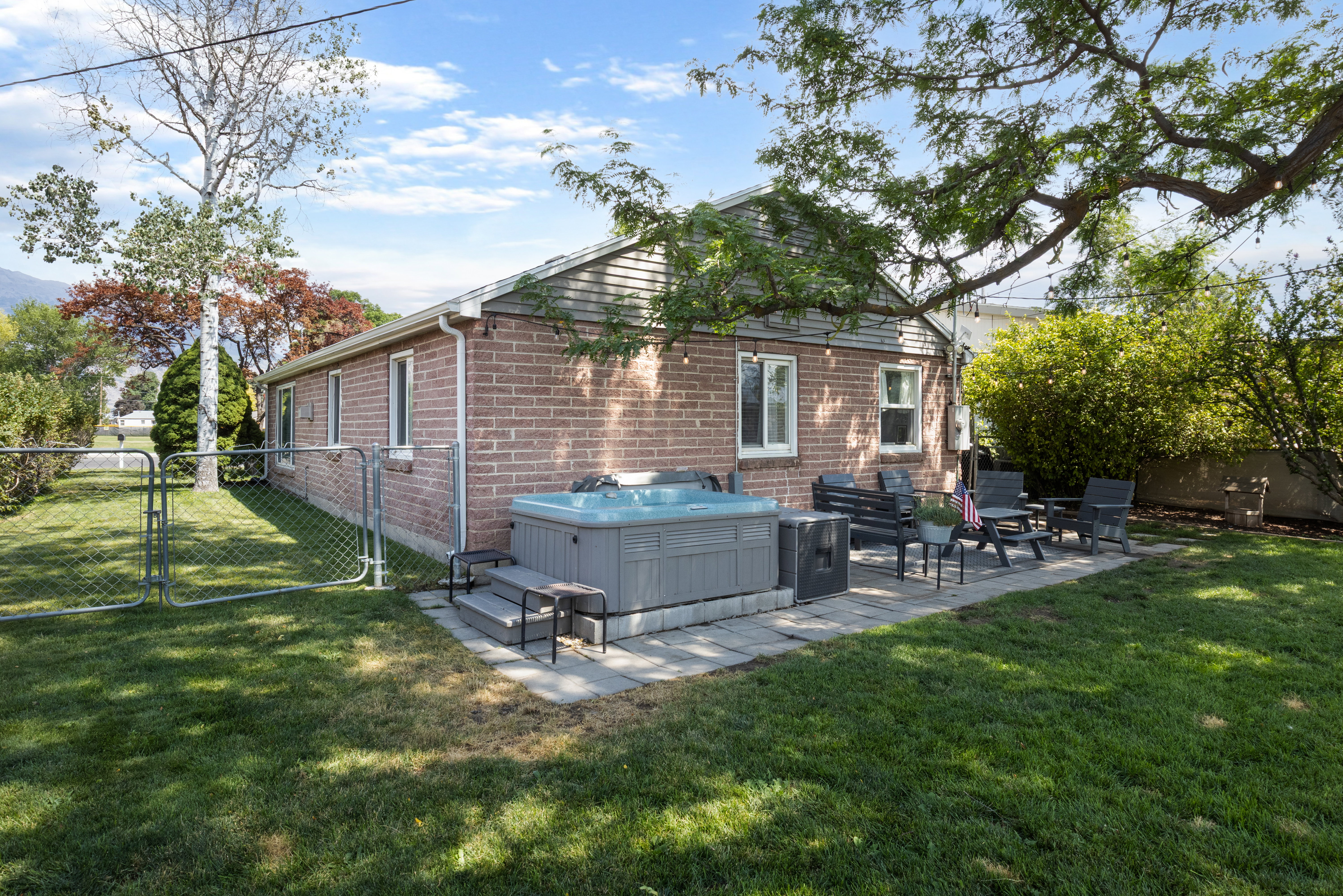 Brick exterior featuring a private hot tub on a paver patio