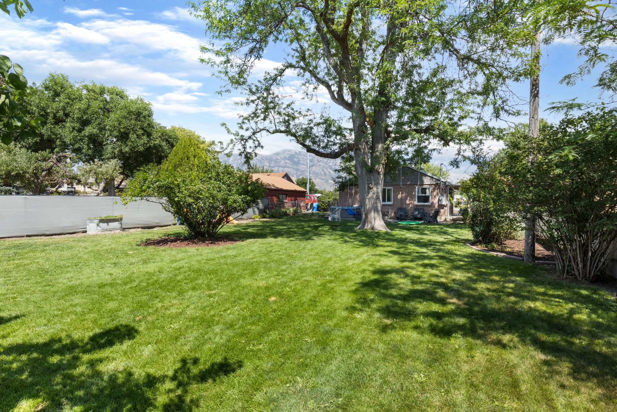 Expansive green lawn with mature trees and established landscaping