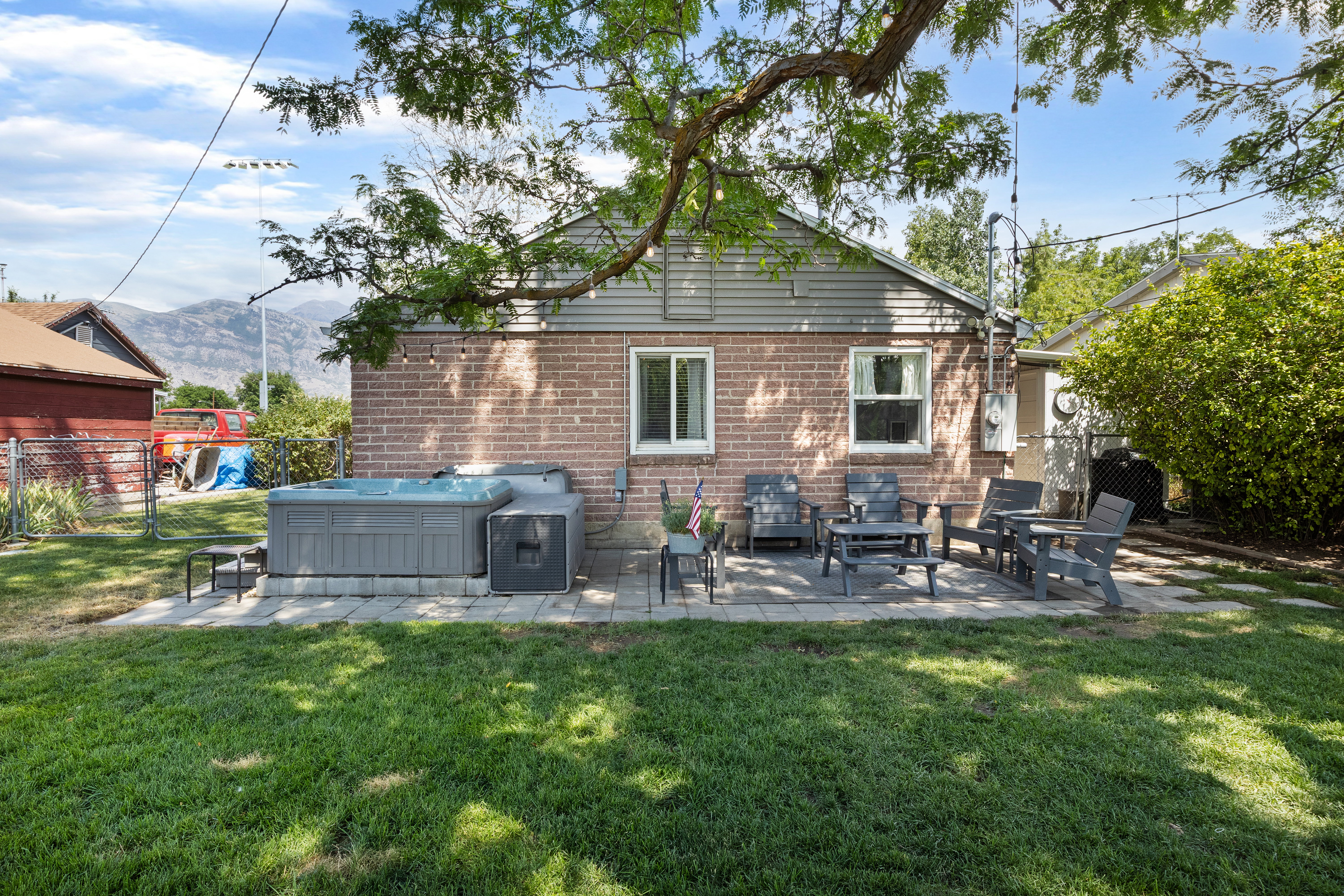 Expansive backyard featuring a brick exterior, a paver patio, and mature trees