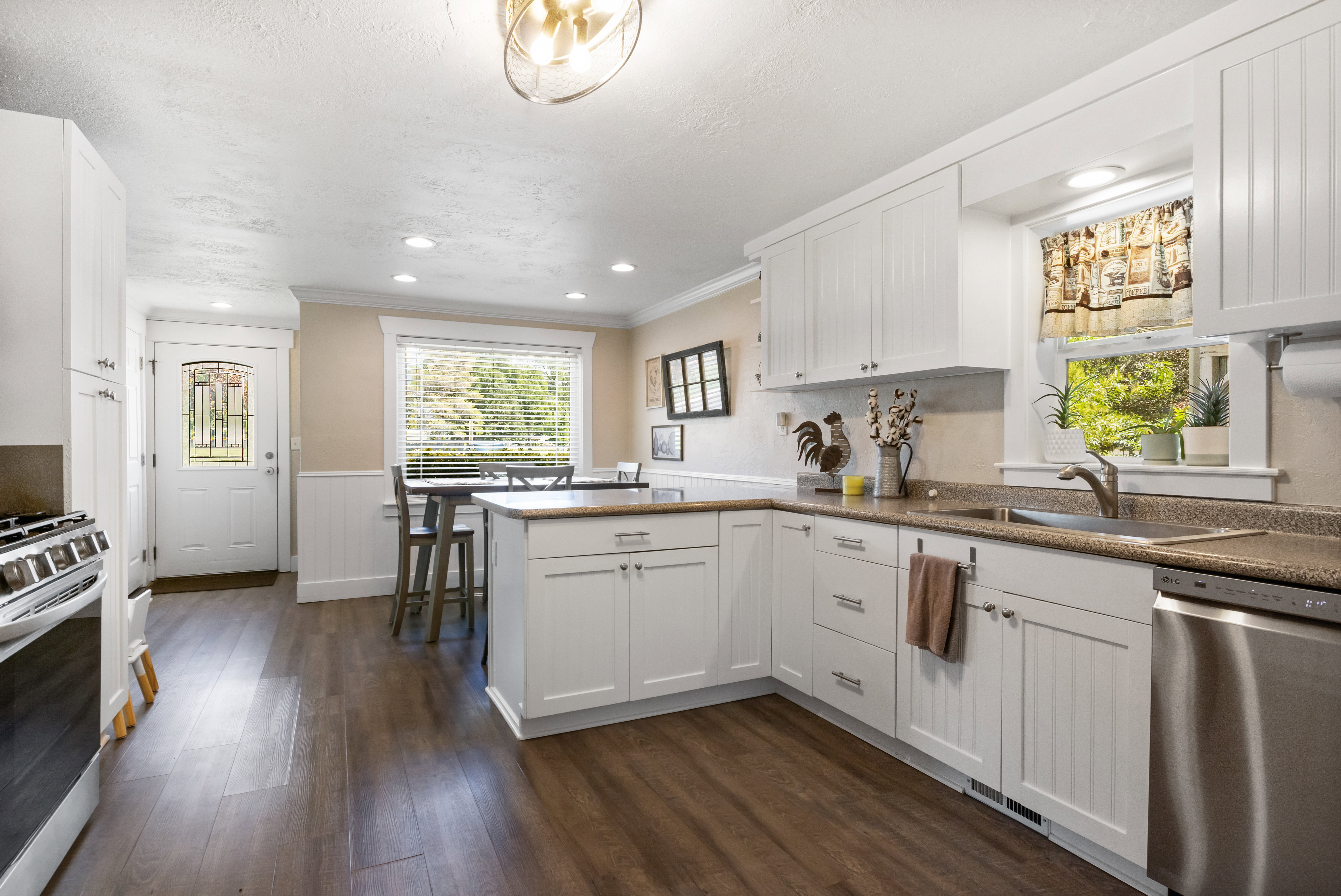 Kitchen featuring white shaker-style cabinetry, wood-finish flooring, recessed lighting, stainless steel dishwasher, and a built-in range