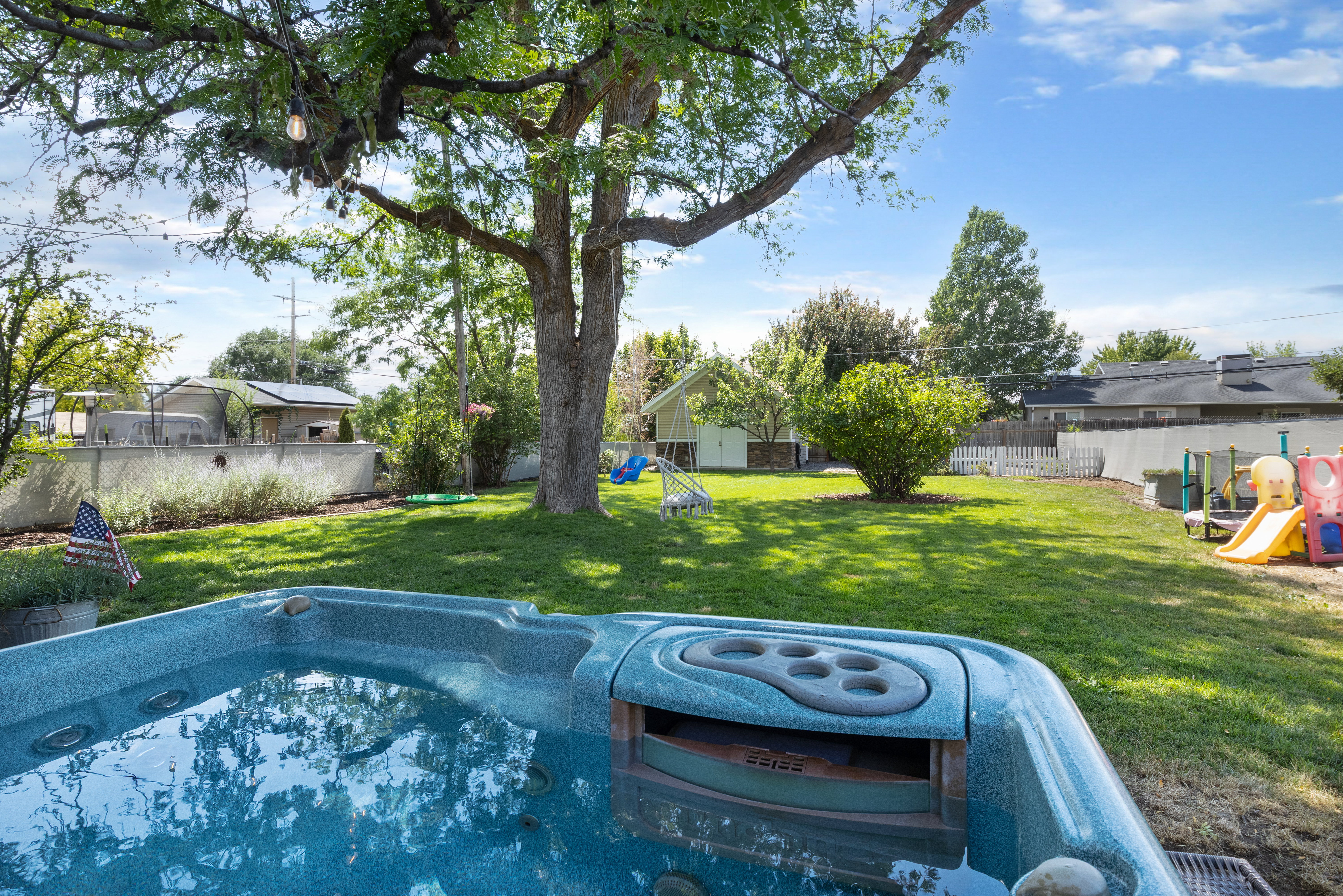 Spacious backyard featuring a built-in spa, mature trees, and a manicured lawn